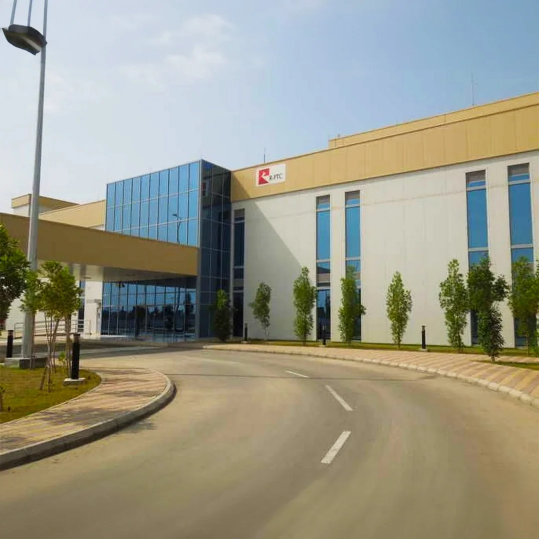 Modern office building with glass windows and PetroRabigh logo, surrounded by small trees and a curved driveway under a partly cloudy sky. مقر بترورابغ الرئيسي