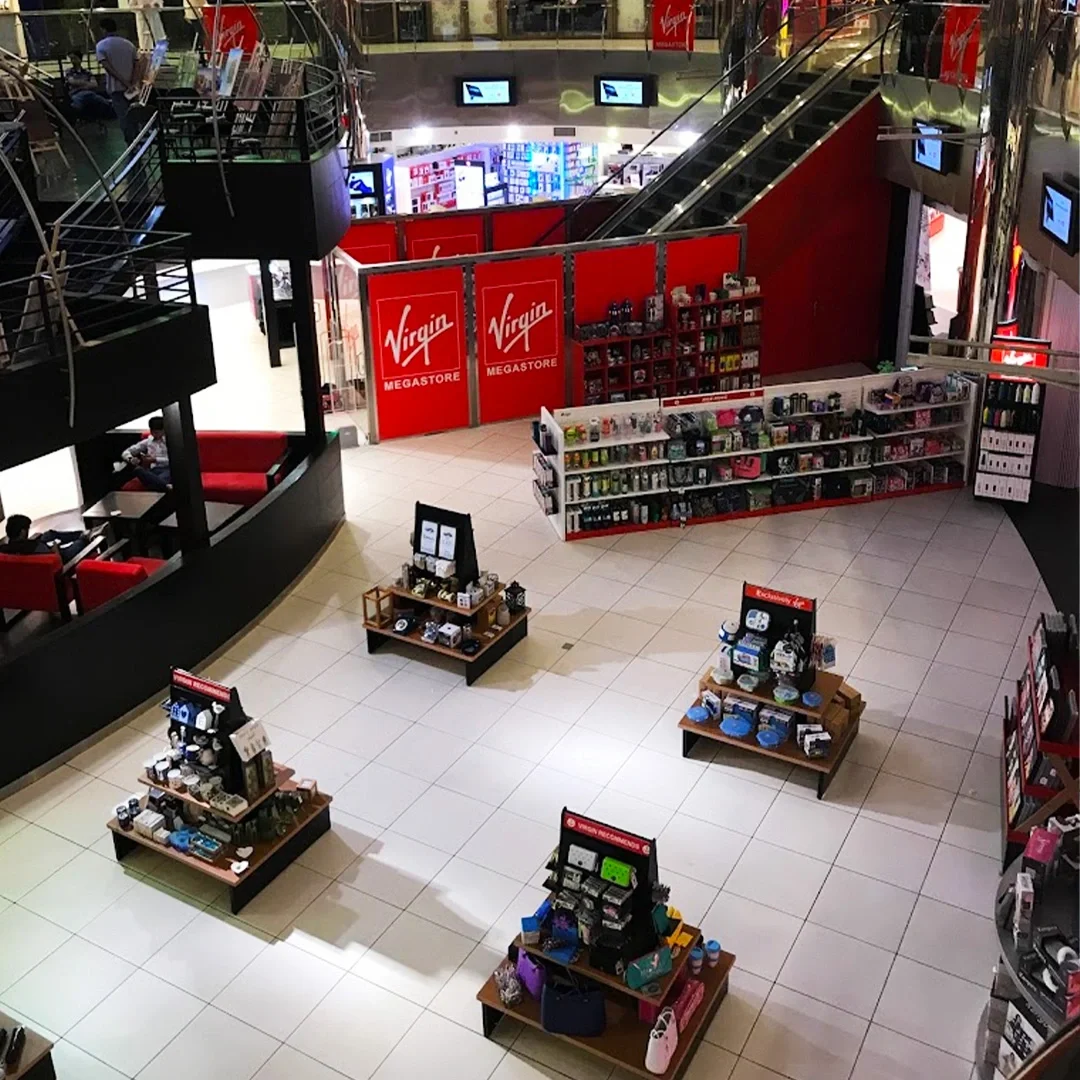 Interior of a shopping mall with a Virgin Megastore kiosk and display stands for electronic accessories and gadgets. فيرجين ميغا ستور