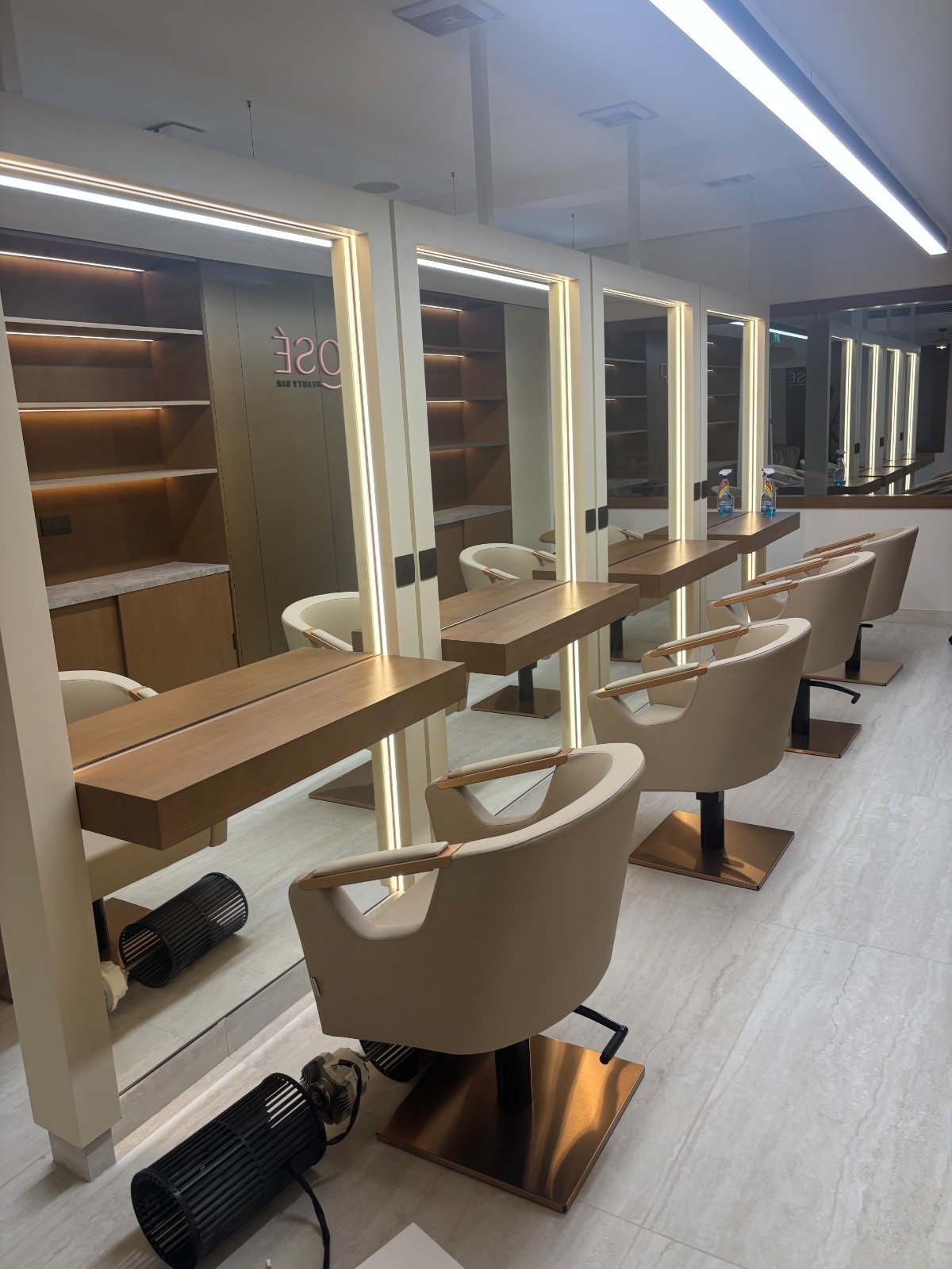 Empty modern beauty salon with styling chairs, mirrors with LED lighting, and wooden workstations. صالون روزيه rose beauty center in jeddah