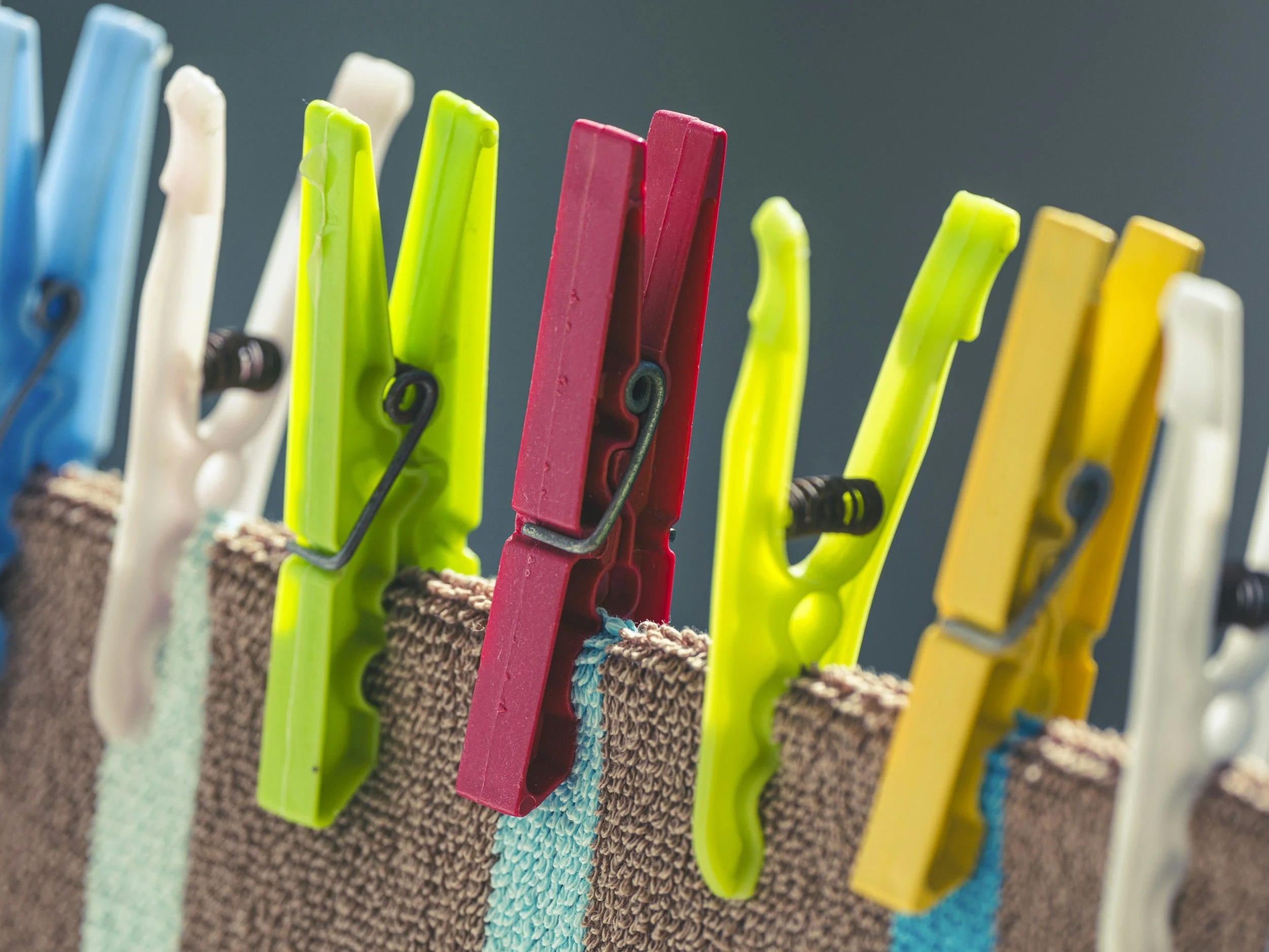 Close-up of colorful clothespins clipped onto a textured fabric surface.