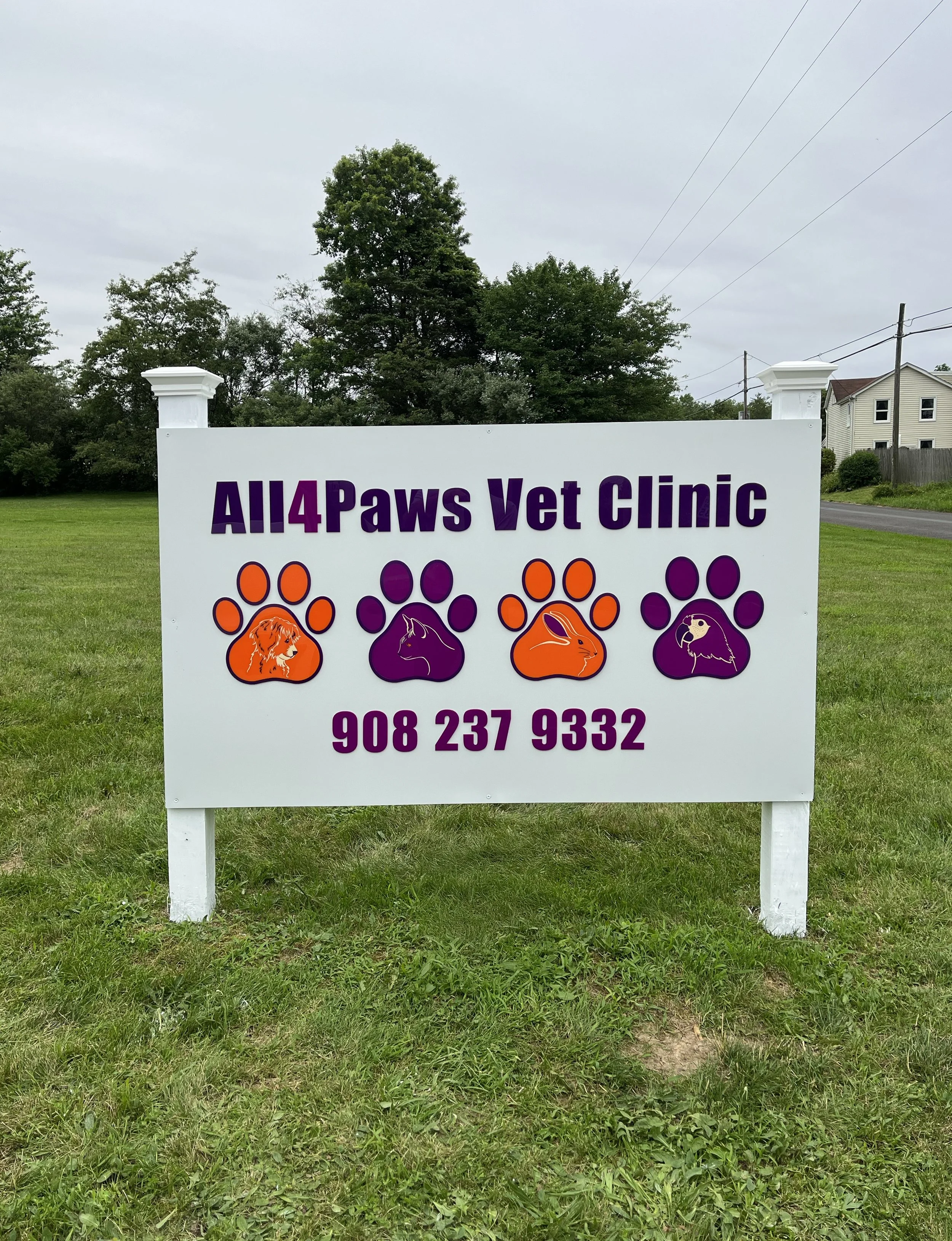 Sign for All4Paws Vet Clinic with four paw prints and animal illustrations inside, including a lion, a cat, a rabbit, and a bird, with the phone number 908 237 9332.