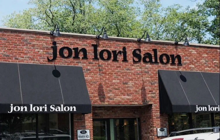 storefront of Jon Lori Salon with brick exterior, black awnings, and signage