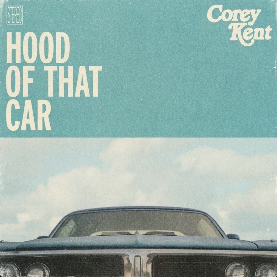 Album cover featuring the front of a vintage car against a light blue sky with some clouds. Text on the cover includes "Hood of That Car" and the artist's name, Corey Kent.