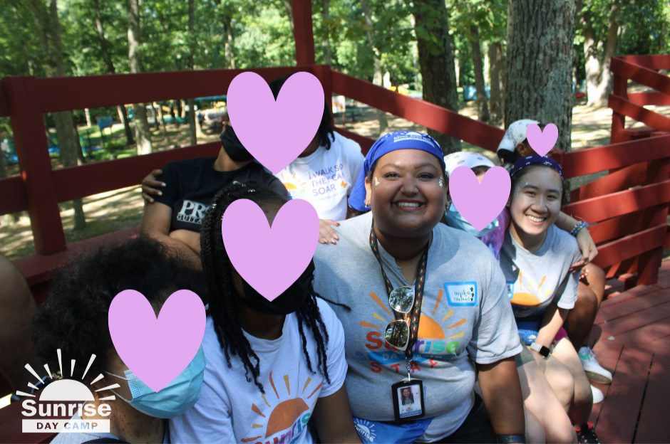 Naomi Nguyen, her co-counselor, and their campers sit on a bench outside.