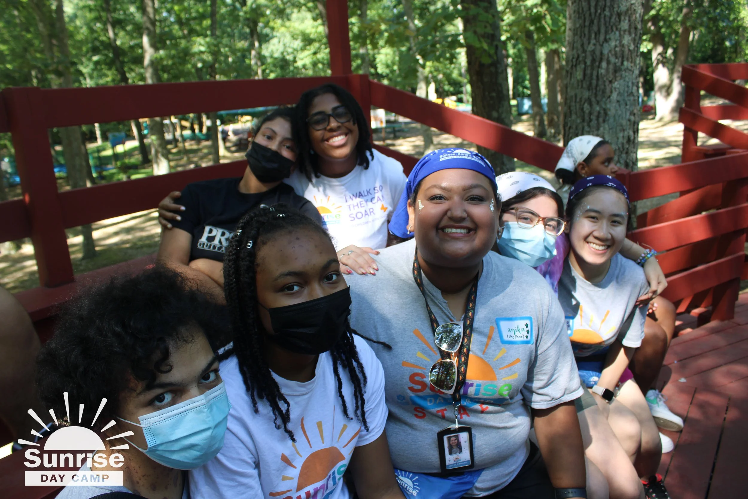 Naomi, her co-counselor, and her campers sitting outside on a bench.