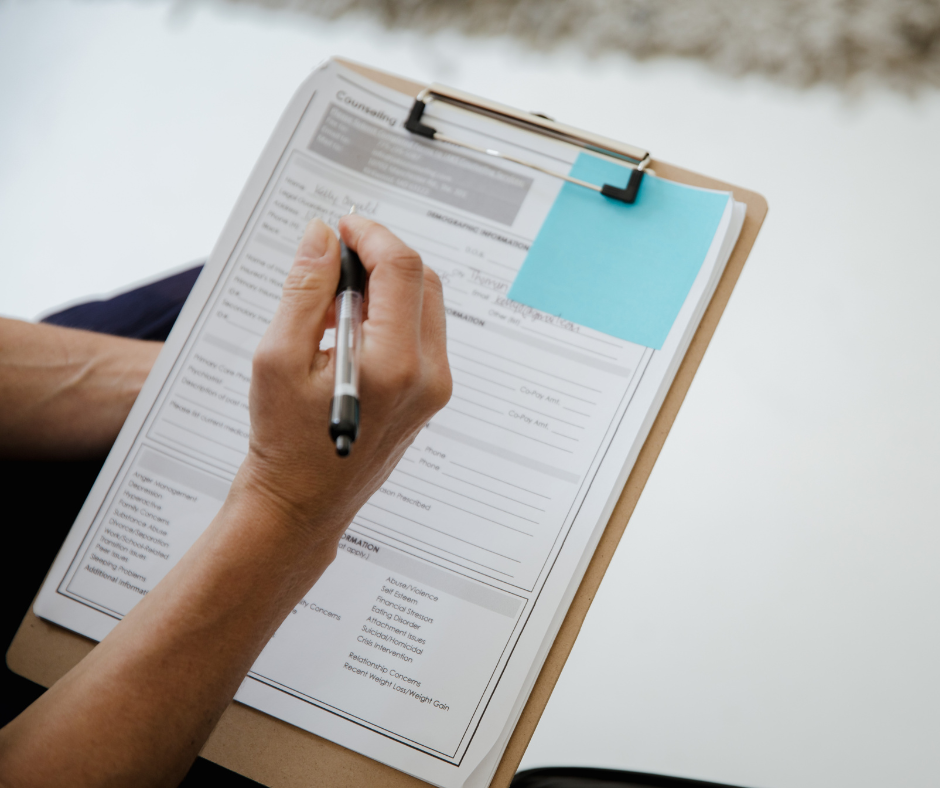 Person filling out a medical insurance form on a clipboard.