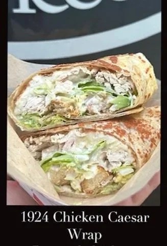 Half of a Chicken Caesar Wrap with lettuce and chicken visible, held in hand.