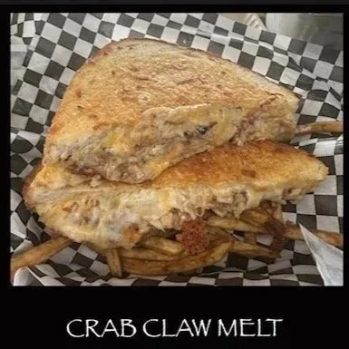 Crab claw melt sandwich with melted cheese and crab meat on toasted bread, served with French fries
