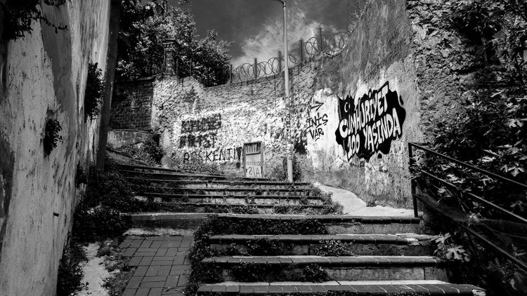 Black-and-white view of outdoor steps rising beside a graffiti-covered wall.