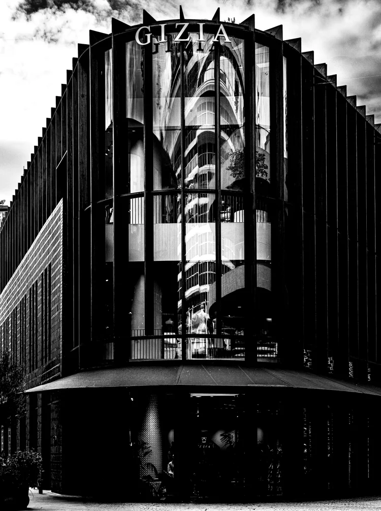 Black-and-white low-angle view of a modern building with tall vertical fins and a glass corner facade.