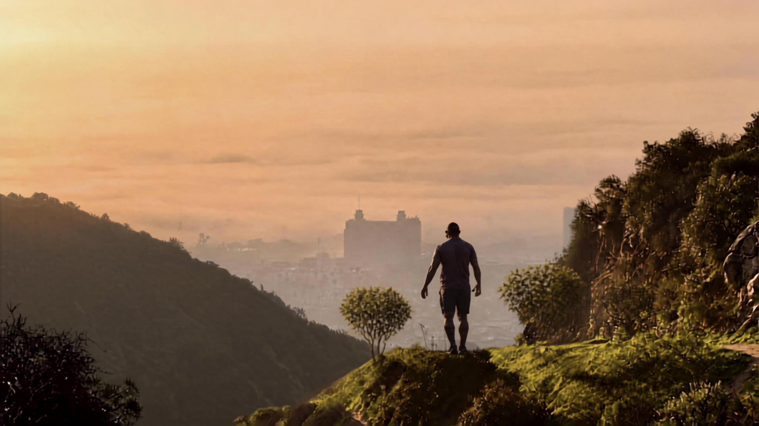 A person walking along a hillside path at sunset or sunrise, with city buildings visible in the distance and a sky filled with warm orange and pink hues.