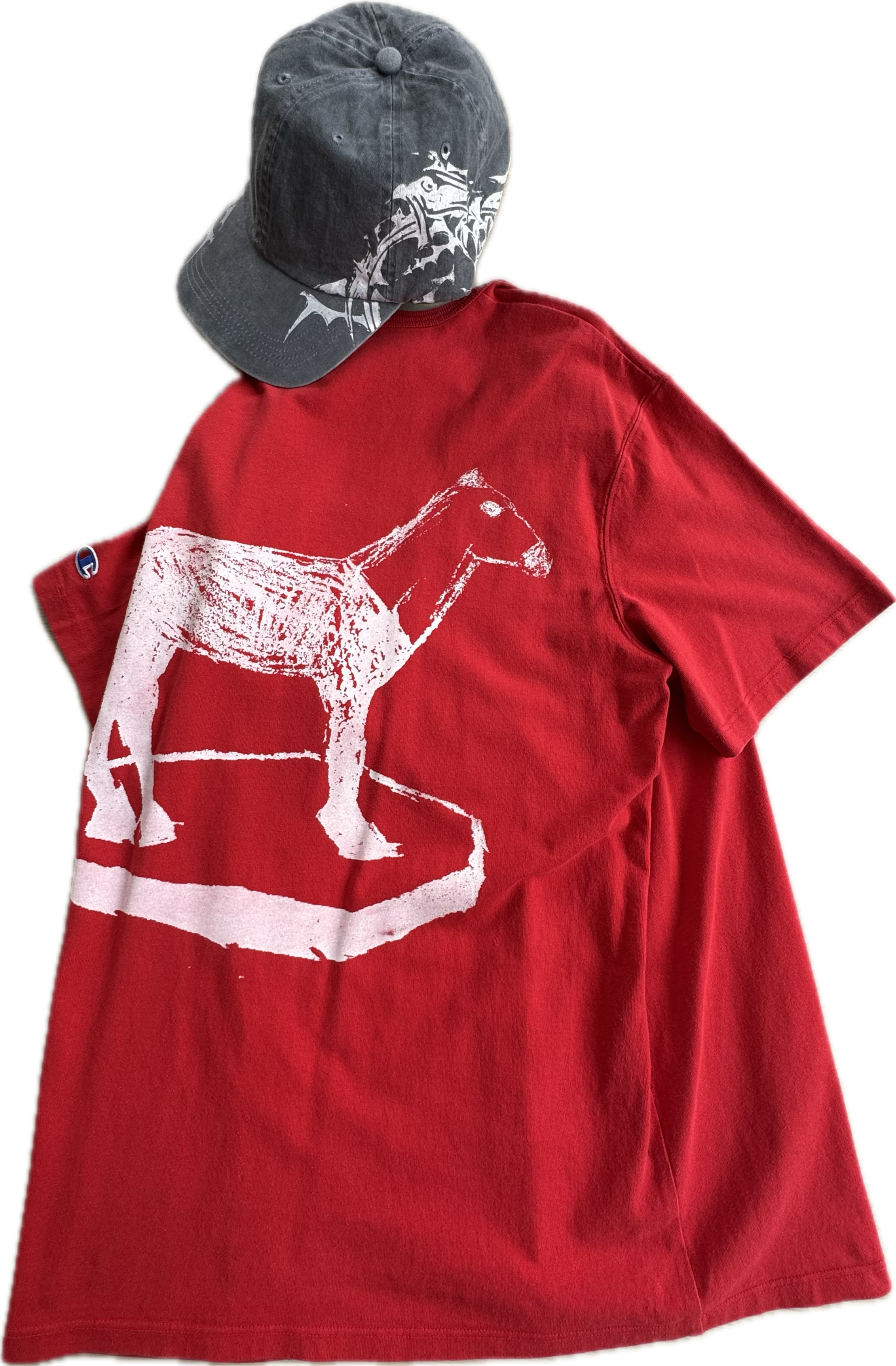 A red T-shirt with a white distressed print of a dog on it, and a black baseball cap with a white design