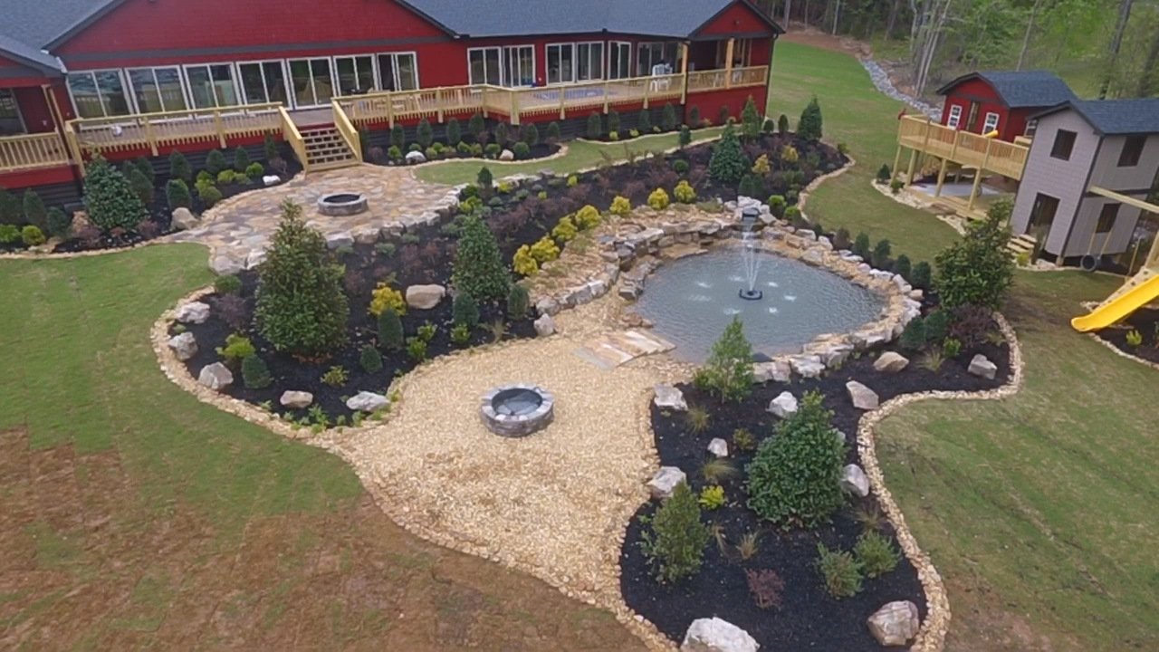A backyard with a landscaped garden, a pond with a fountain, and a firepit, adjacent to a red house with a large deck.