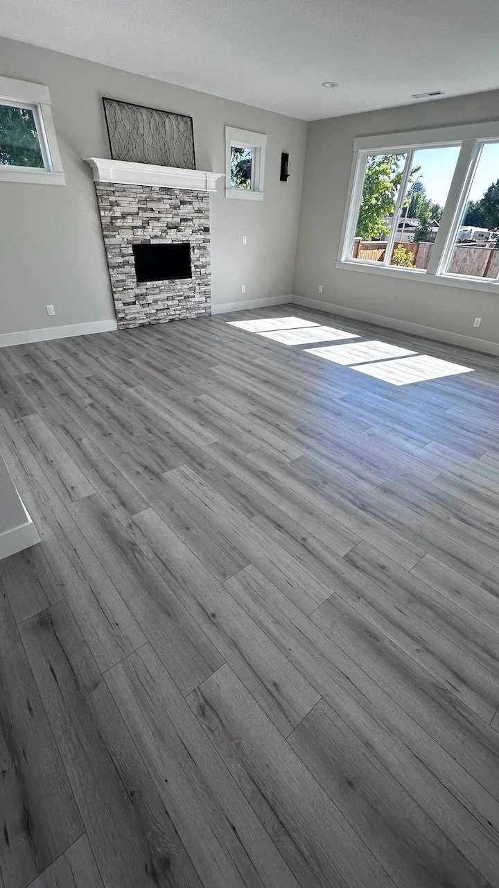 Sannikov LLC flooring project: light plank floors in a bright living room with a white fireplace