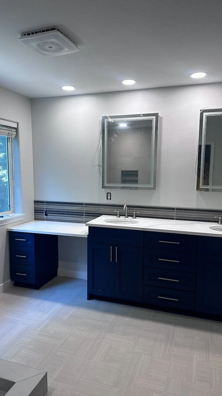 Bathroom with a blue vanity, white countertop and bright finishes.