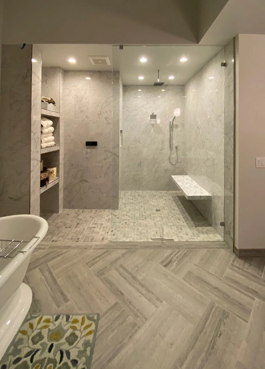Spacious bathroom with herringbone flooring, a freestanding tub and tiled shower.