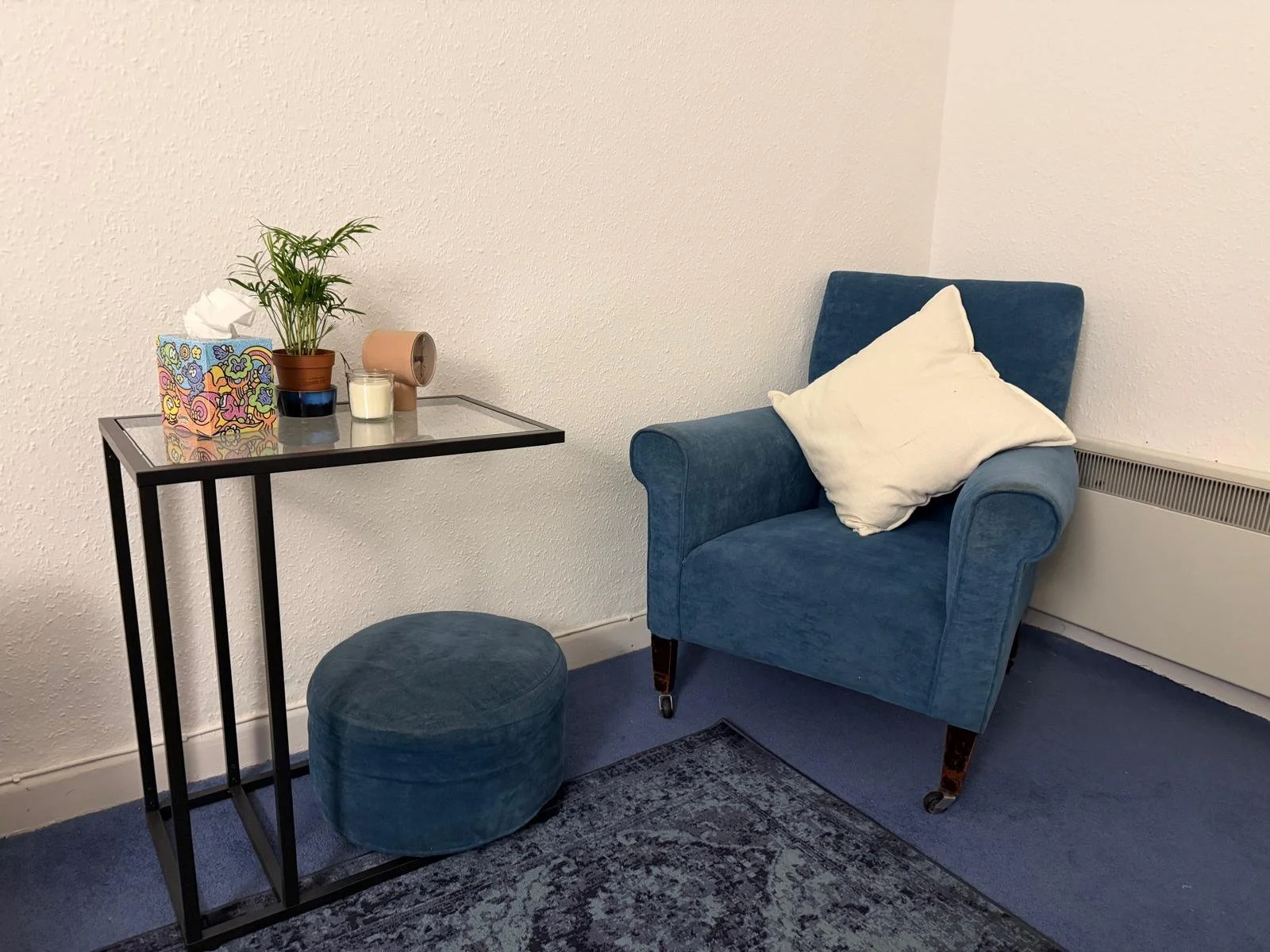 Psychotherapy room to rent in Dublin. Flexible, no monthly minimums. Heart of Dublin. The room has textured white walls, a blue carpet, and a white radiator.
