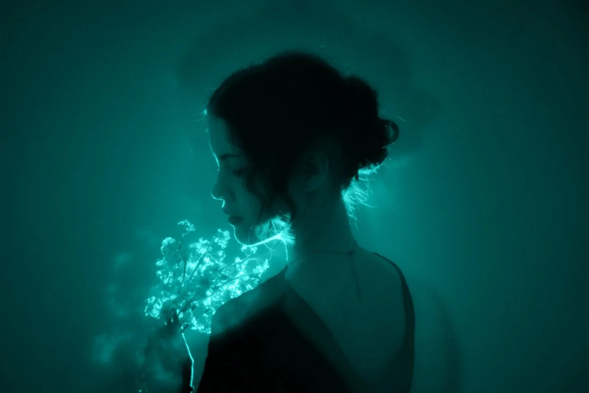 Backlit woman holding flowers, symbolising inner magic, self-love, and personal healing