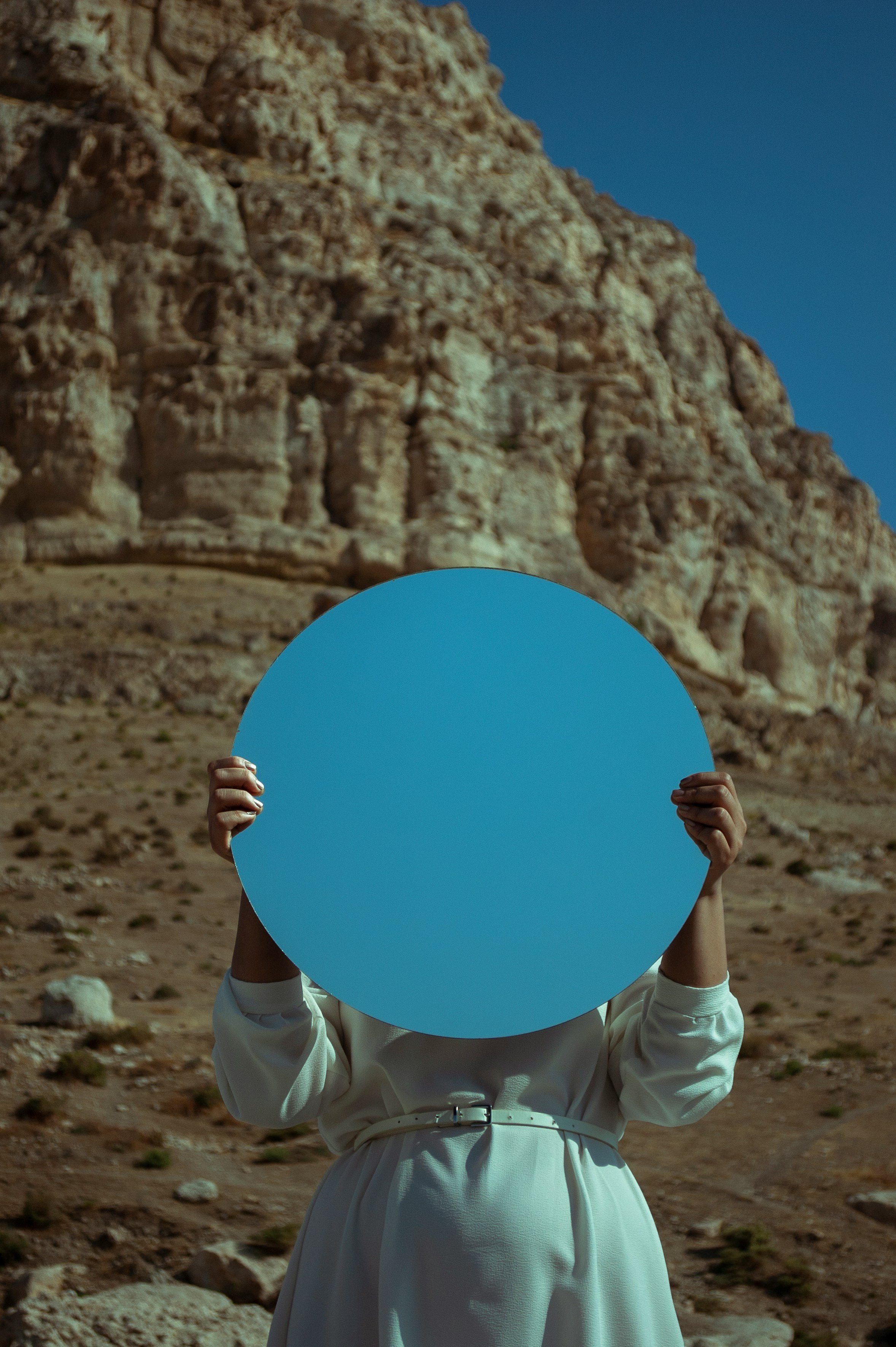 Personne tenant un miroir devant son visage illustrant une réflexion sur l’identité et la perception de soi en thérapie