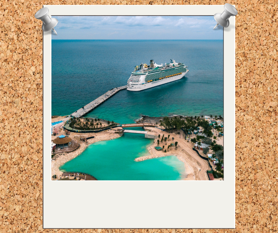 A cruise ship docked at a pier near a turquoise tropical beach with palm trees and a sandy shoreline.