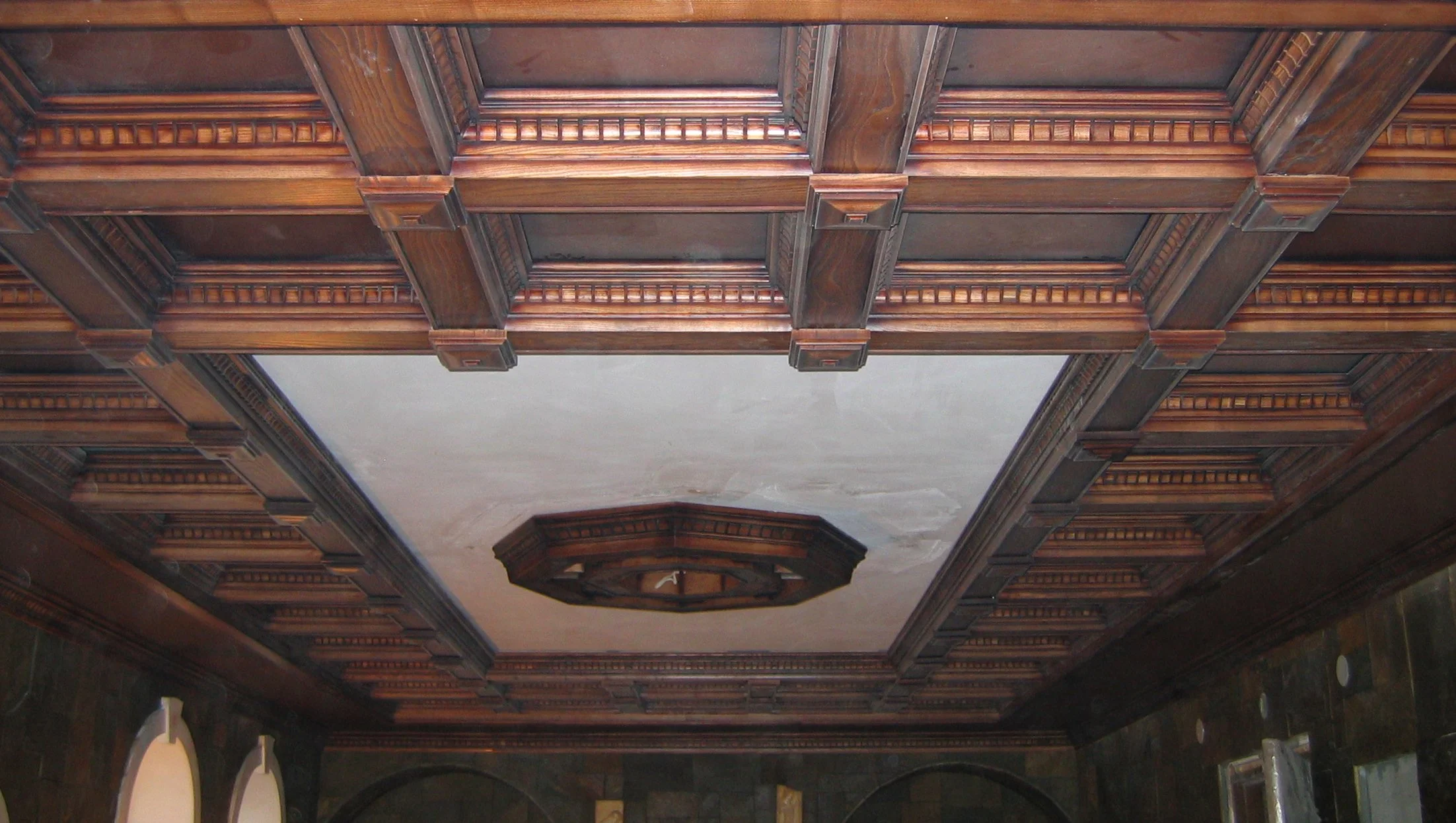 Decorative wooden ceiling with intricate molding and a central octagonal light fixture.