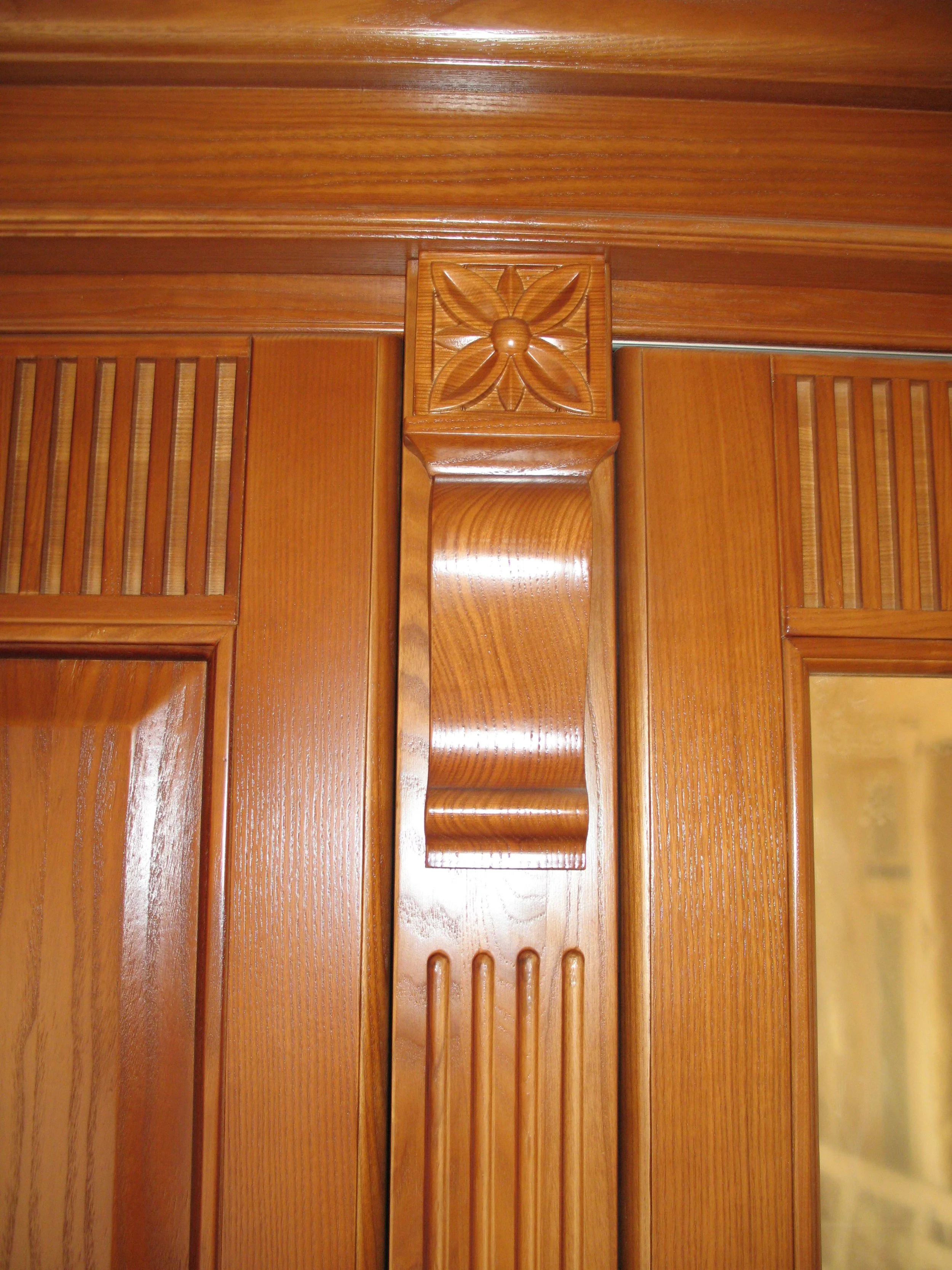 Close-up of a decorative wooden furniture or panel with intricate carved details and a glossy finish.