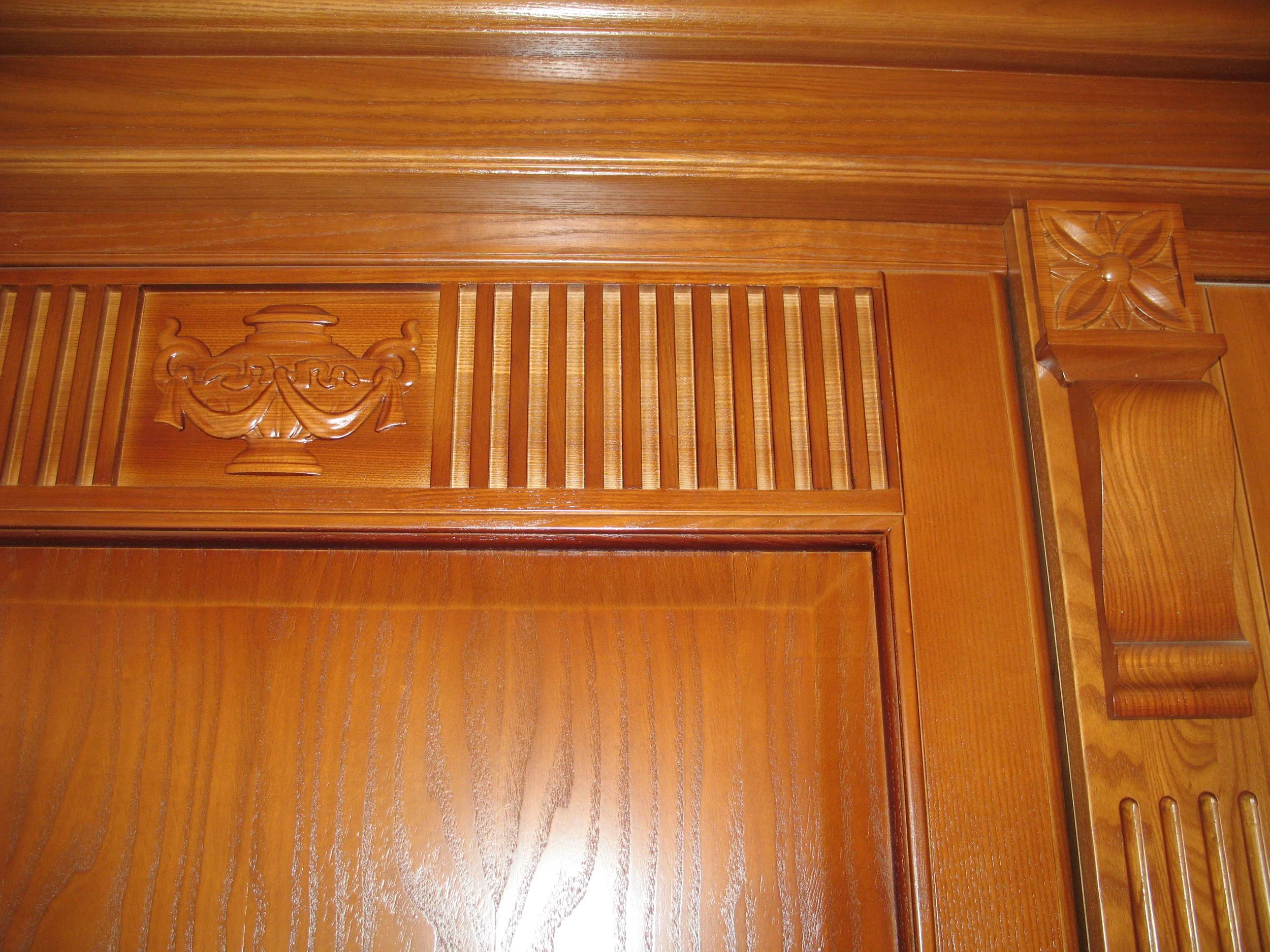Close-up of intricately carved wooden panel with floral and urn patterns, part of a wooden furniture or wall panel.