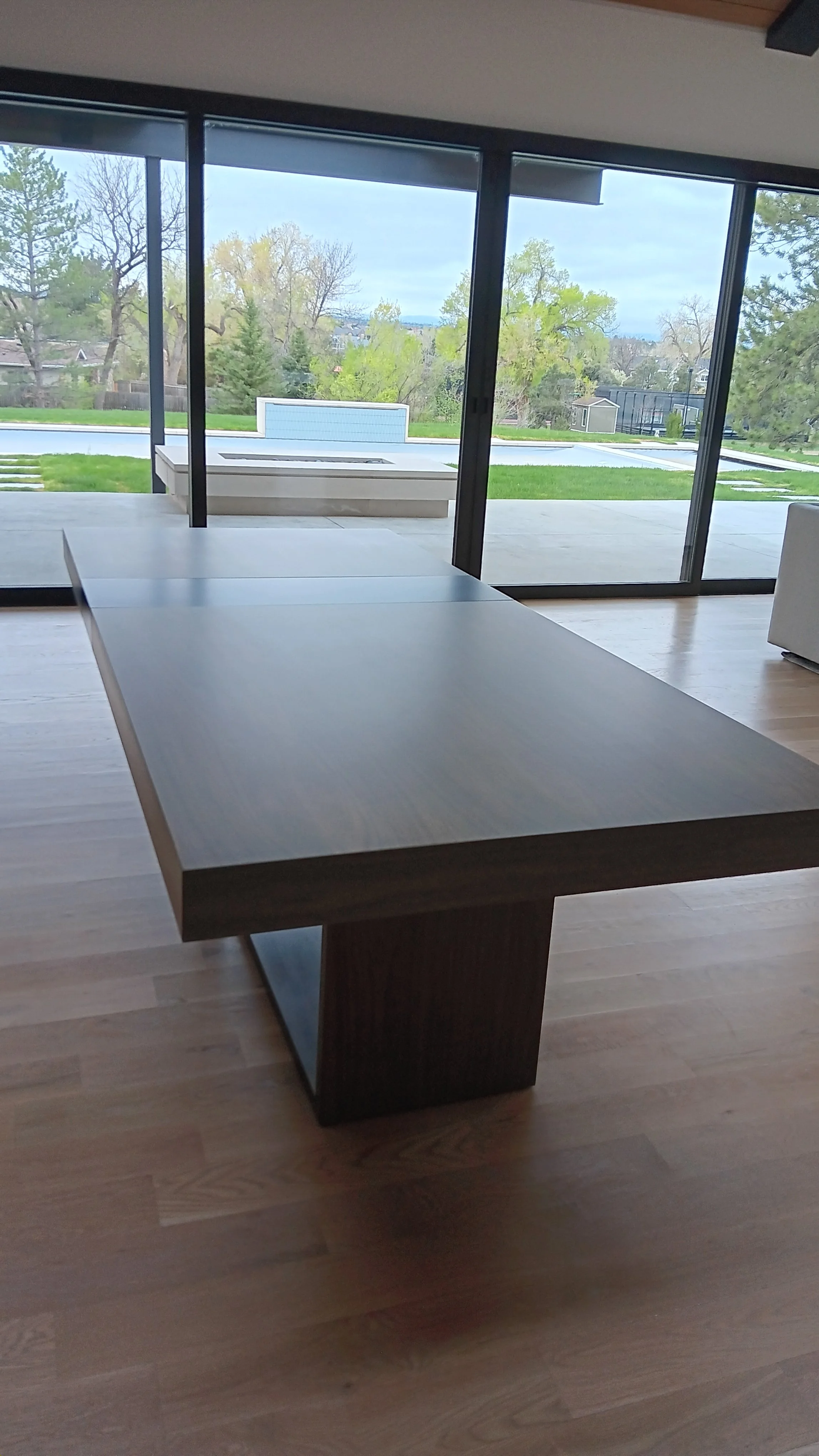 Modern living room with sliding glass doors leading to backyard with pool and trees.