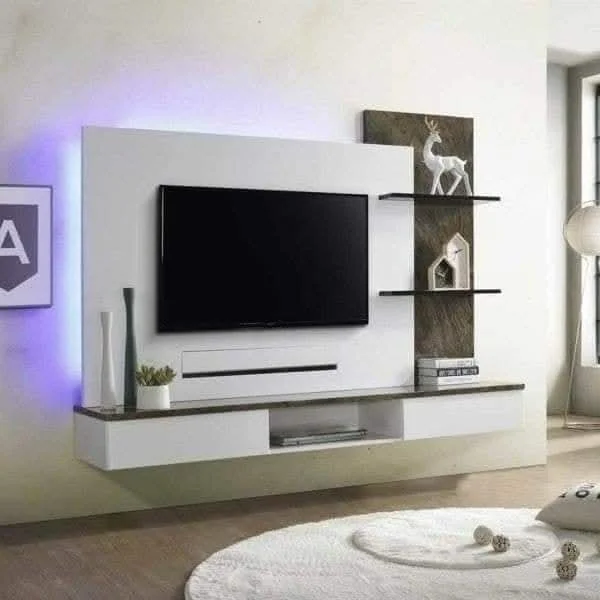 Modern living room entertainment wall with television, shelves, decorative items, and a sitting area with a light-colored rug.