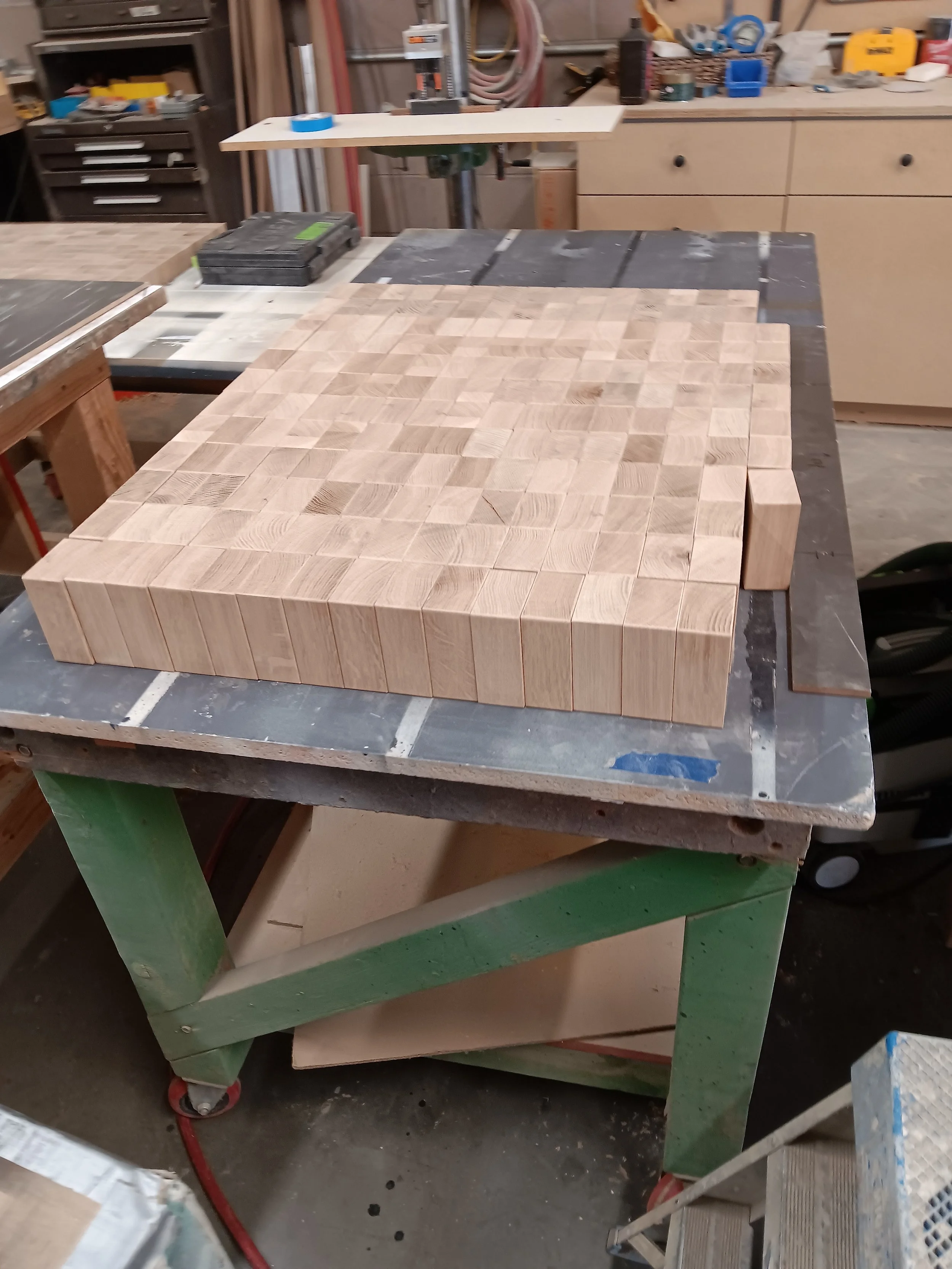 Workbench with a grid of small wooden blocks arranged on it in a workshop.