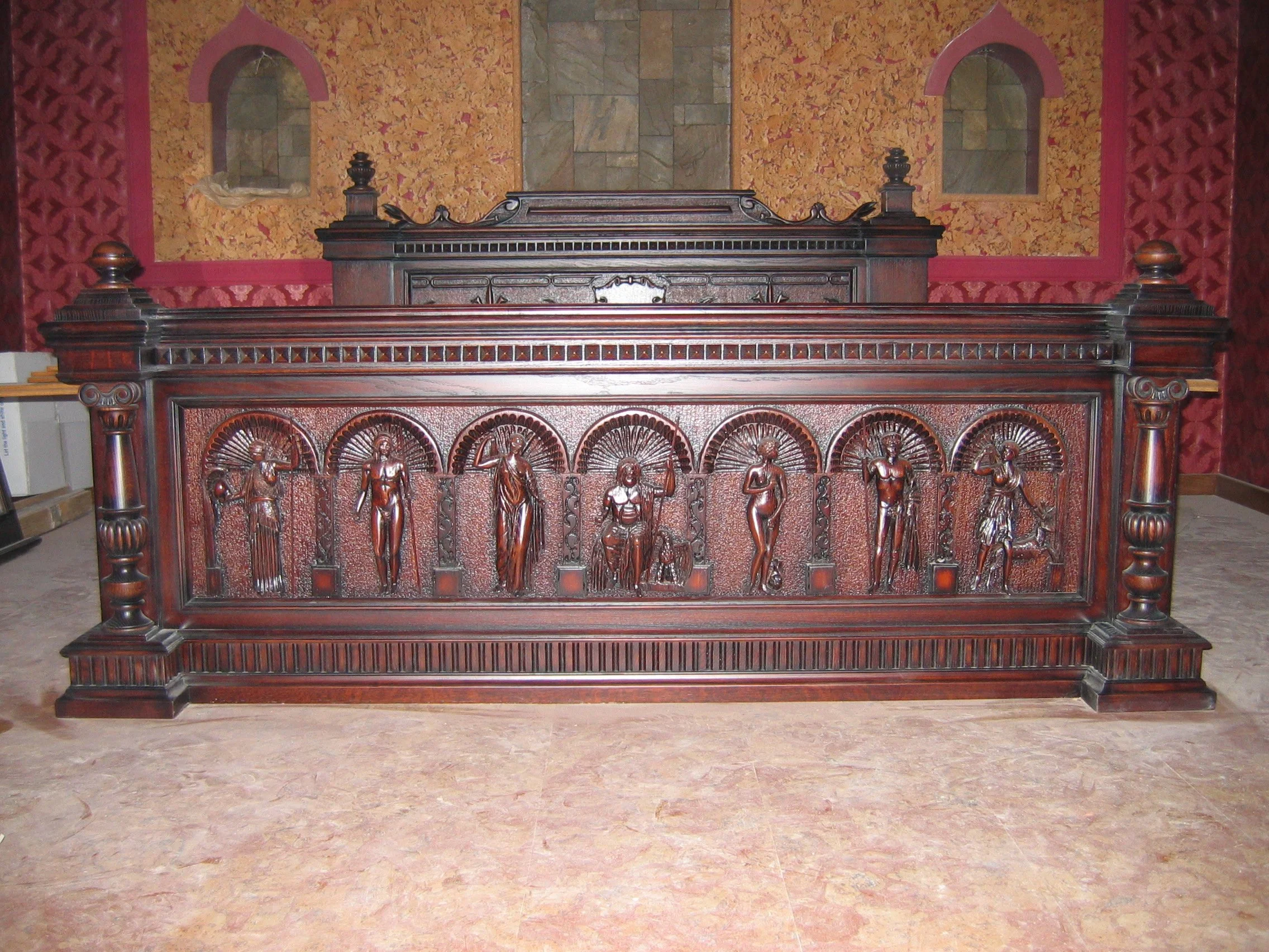A large, ornate wooden altar with carved figures of saints or religious figures, set against a textured wall with two small arched niches.
