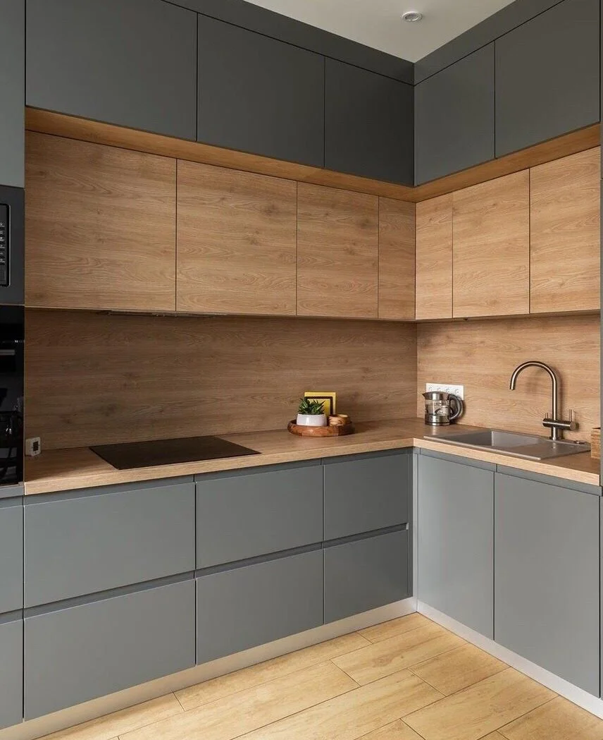 Modern kitchen with light wood and gray cabinets, a sink with a faucet, a knife holder, and a small decorative plant on the counter.