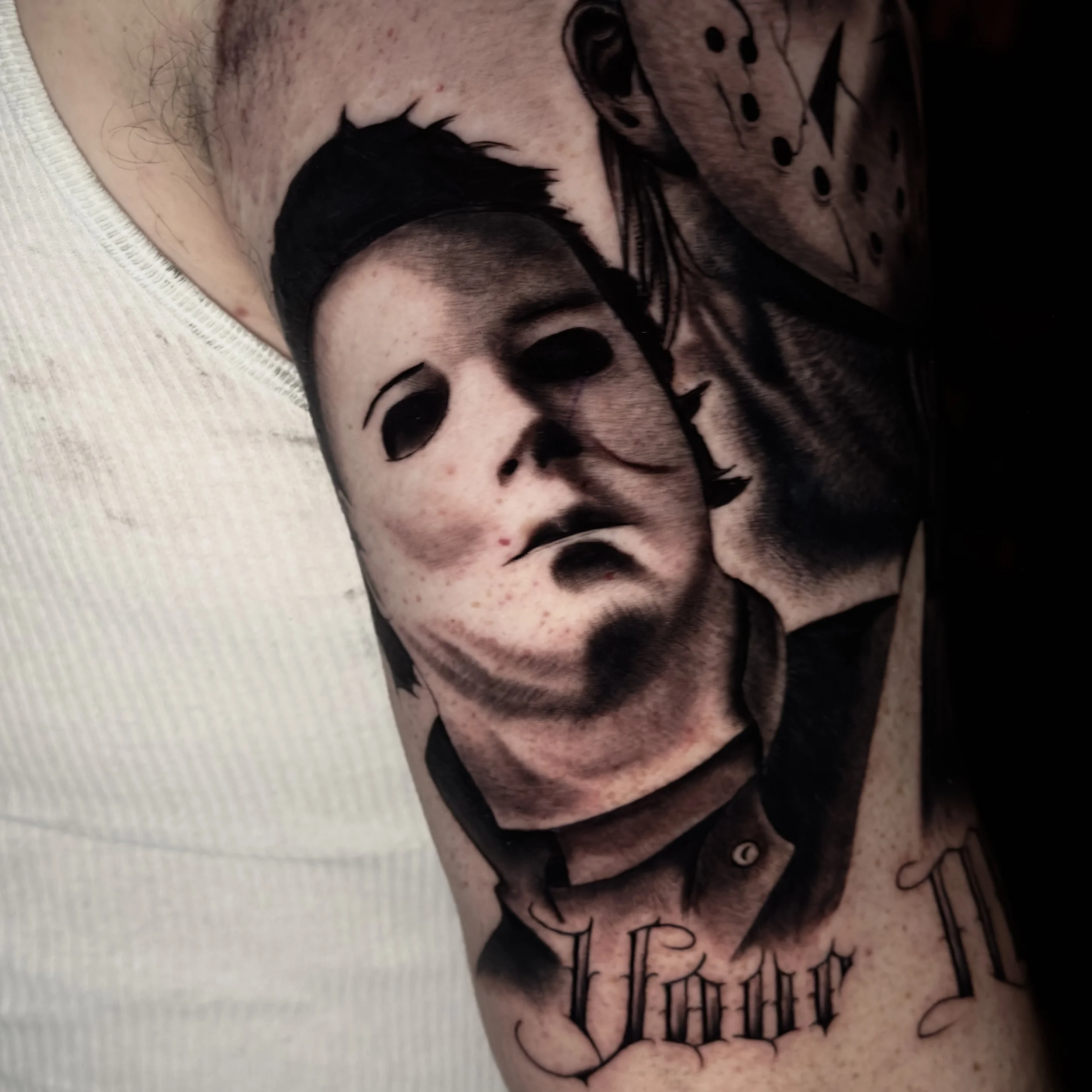 Tattoo of a realistic face of a woman with dark hair and a somber expression on an arm.