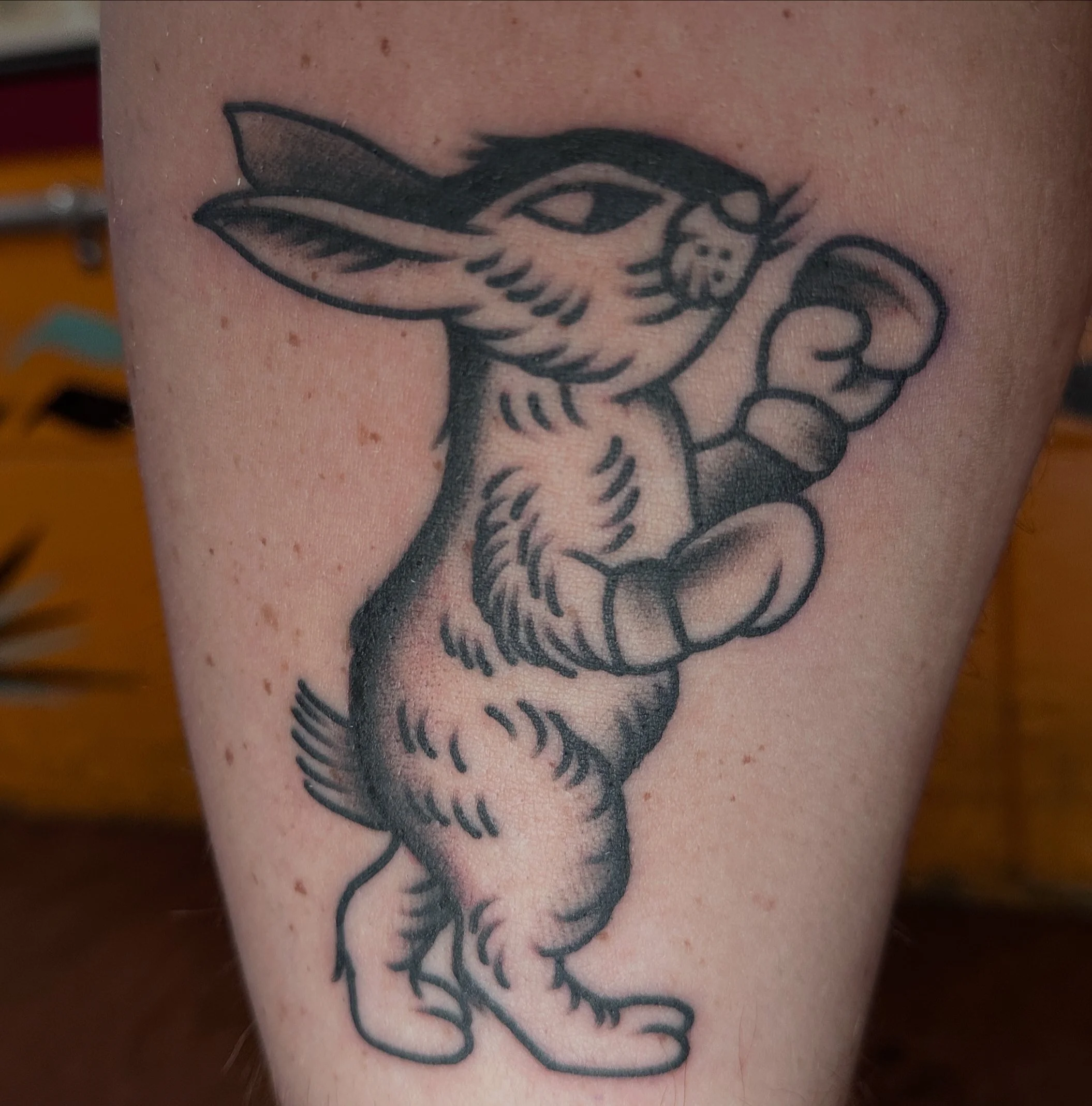 Tattoo of a cartoon rabbit with boxing gloves, standing on its hind legs with one arm raised.