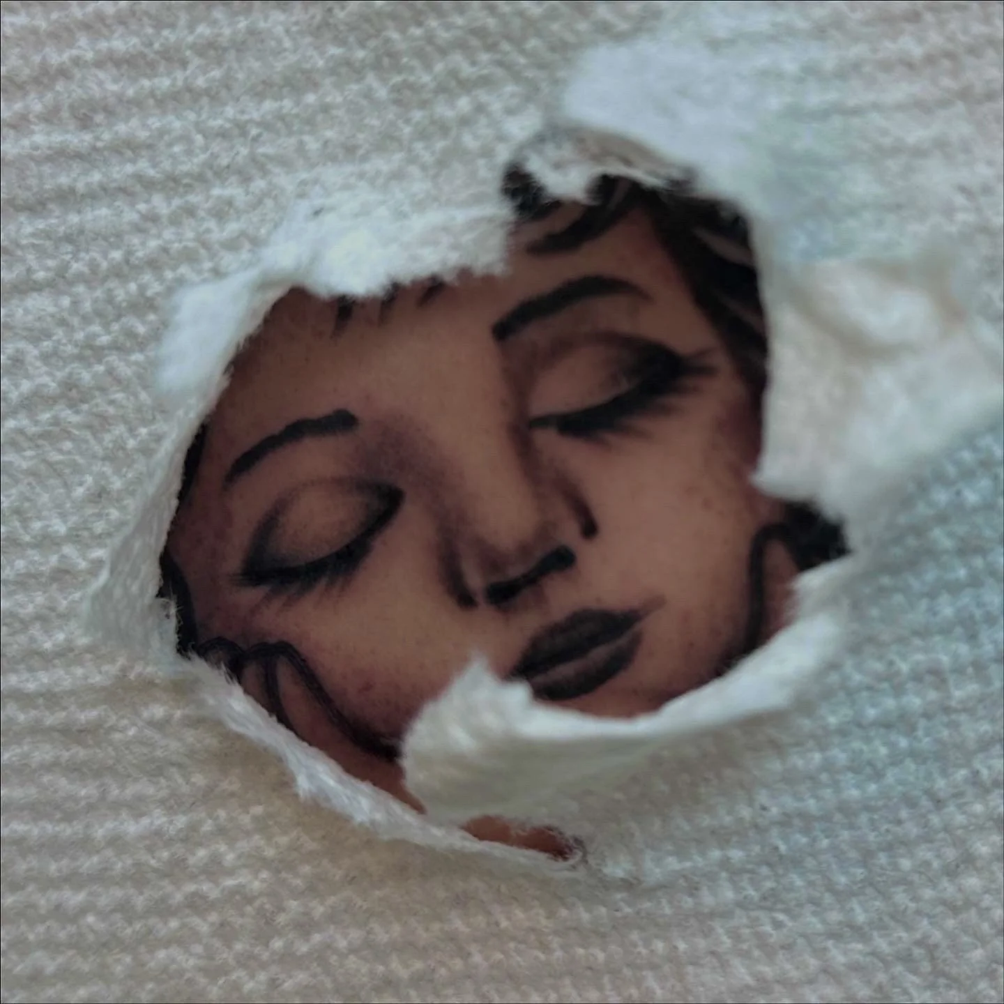 A close-up of a person's face with makeup, seen through a torn piece of white fabric or paper.
