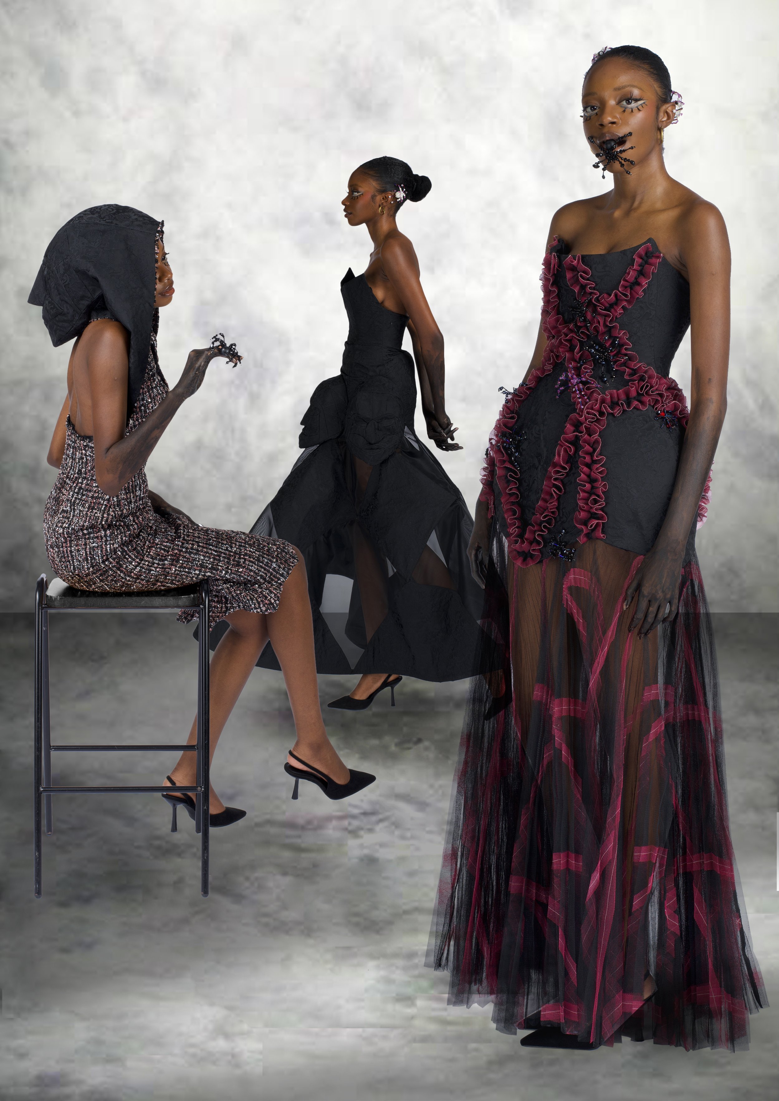Three women wearing elaborate black and red fashion outfits with artistic makeup, set against a gray textured background.