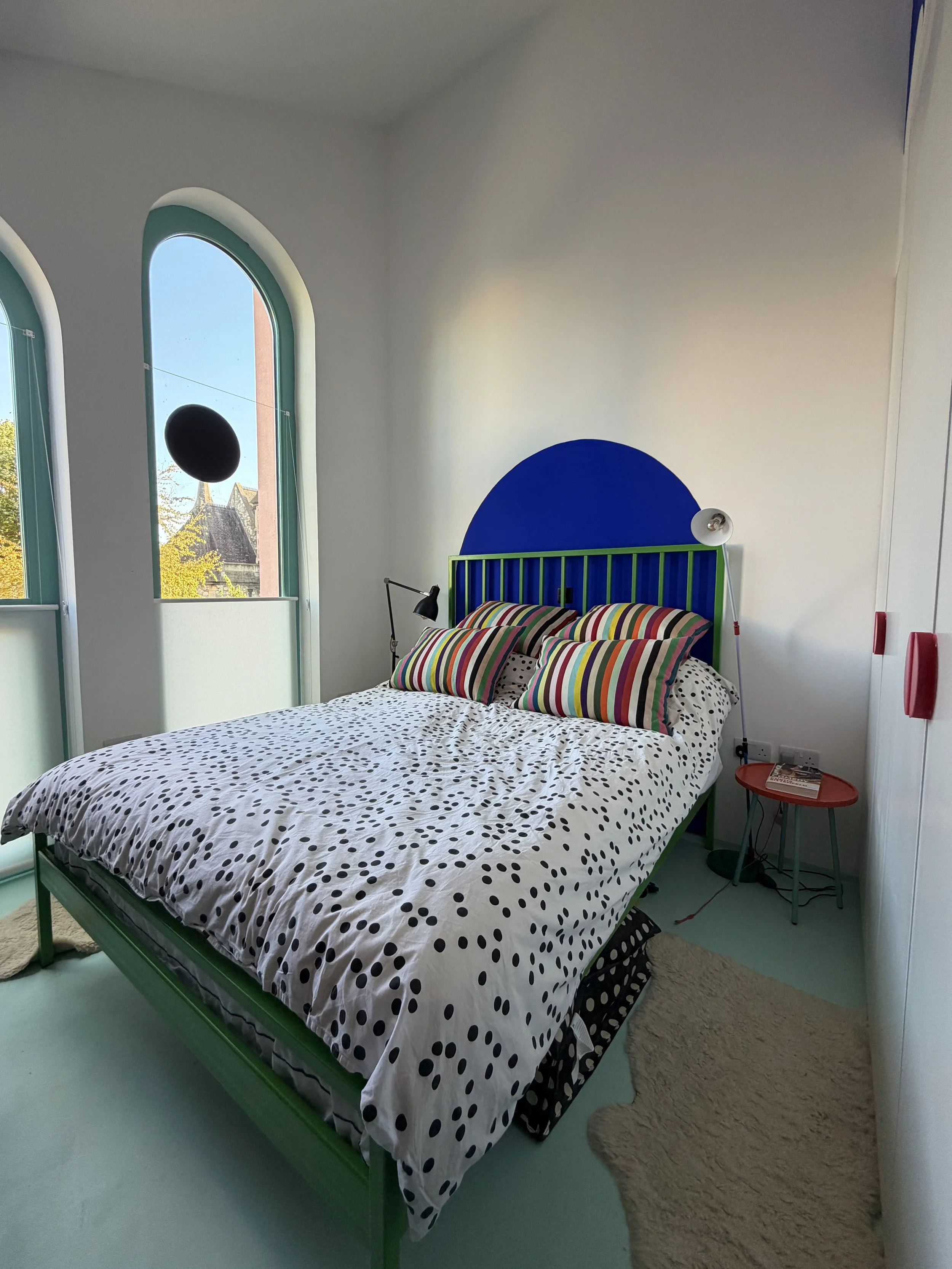 Bedroom inside Cloud House with arched windows, colourful striped textiles and geometric furniture