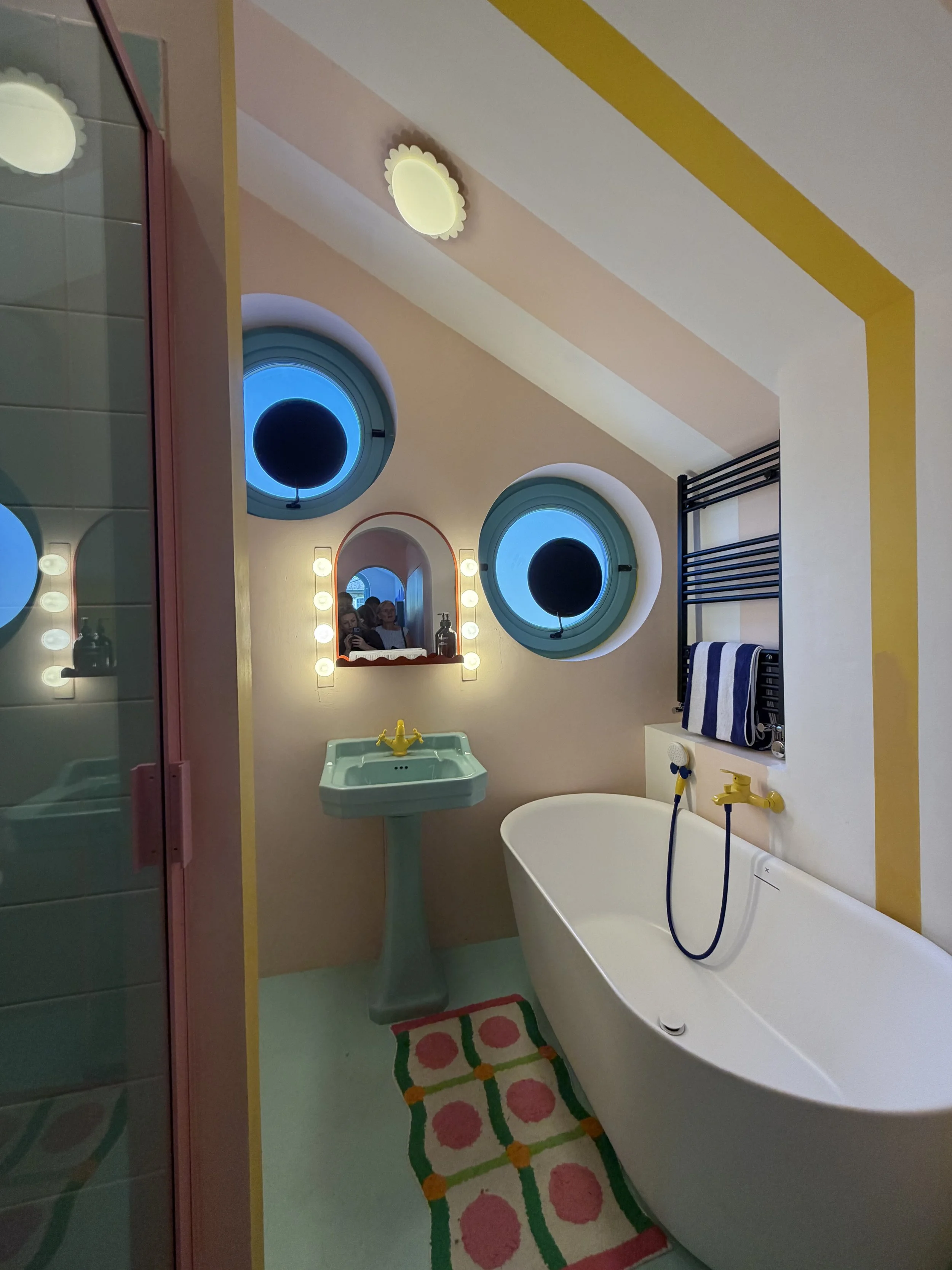 Colourful bathroom inside Cloud House with circular windows, pastel finishes and playful geometric details