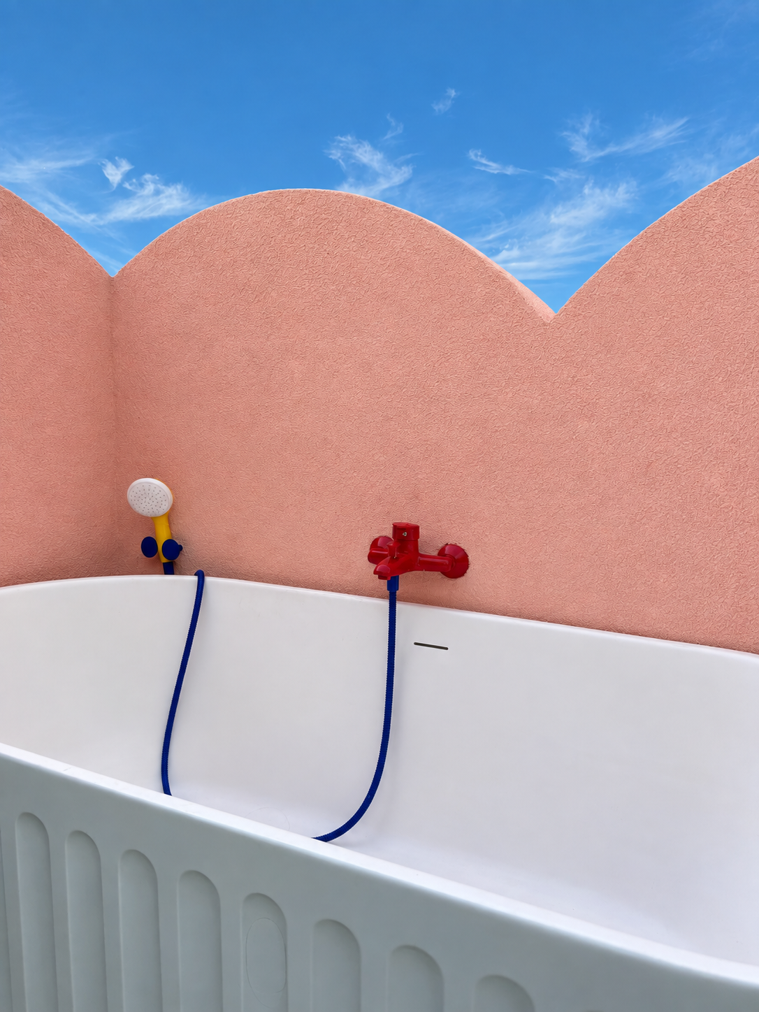 Outdoor bathtub on the Cloud House rooftop terrace surrounded by scalloped pink walls