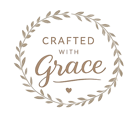Decorative emblem featuring the text "Crafted with Grace" inside a circular wreath of leaves with a small heart below.