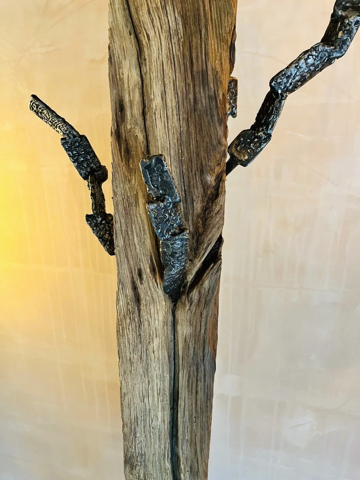 A close-up of a piece of wood with black metal braces or repairs on it, possibly part of a piece of furniture or a wooden beam.