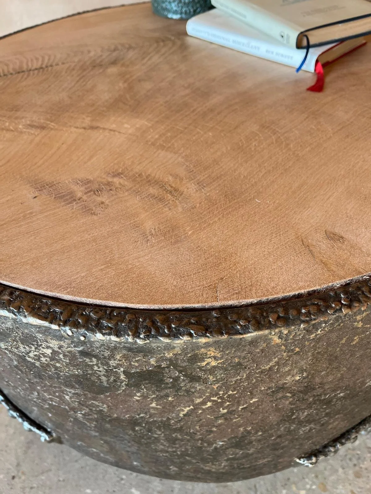 Close-up of a wooden table with a book and a glass jar on top, showing the textured edge of the table.