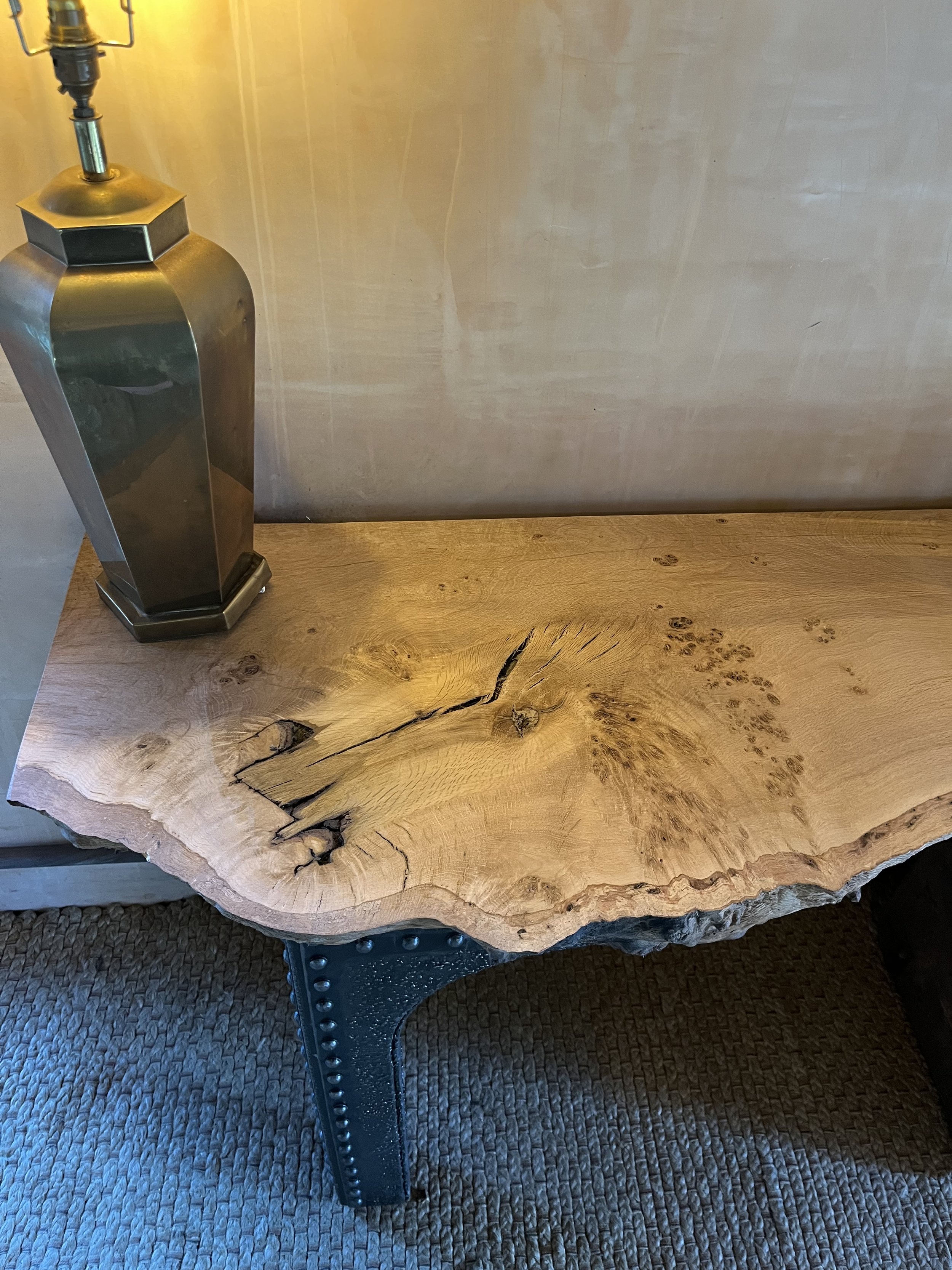 Wooden side table with a natural edge, metal legs, and a metallic table lamp on top.