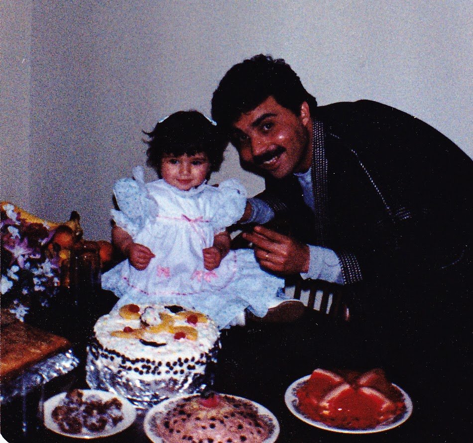 A man and a young girl celebrating a birthday with cakes and fruit.