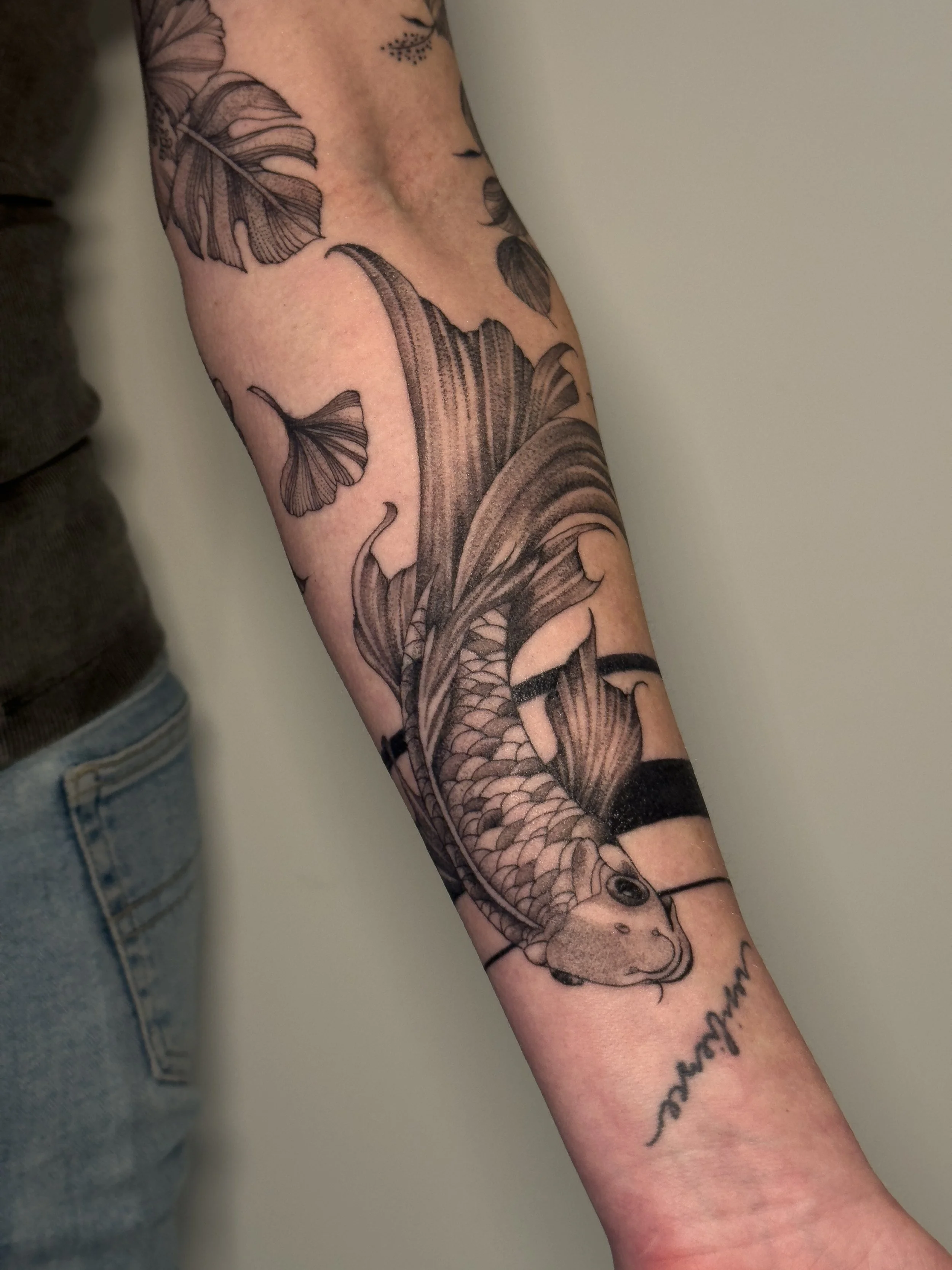 Black and gray tattoo of a fish and butterflies on a person's arm.