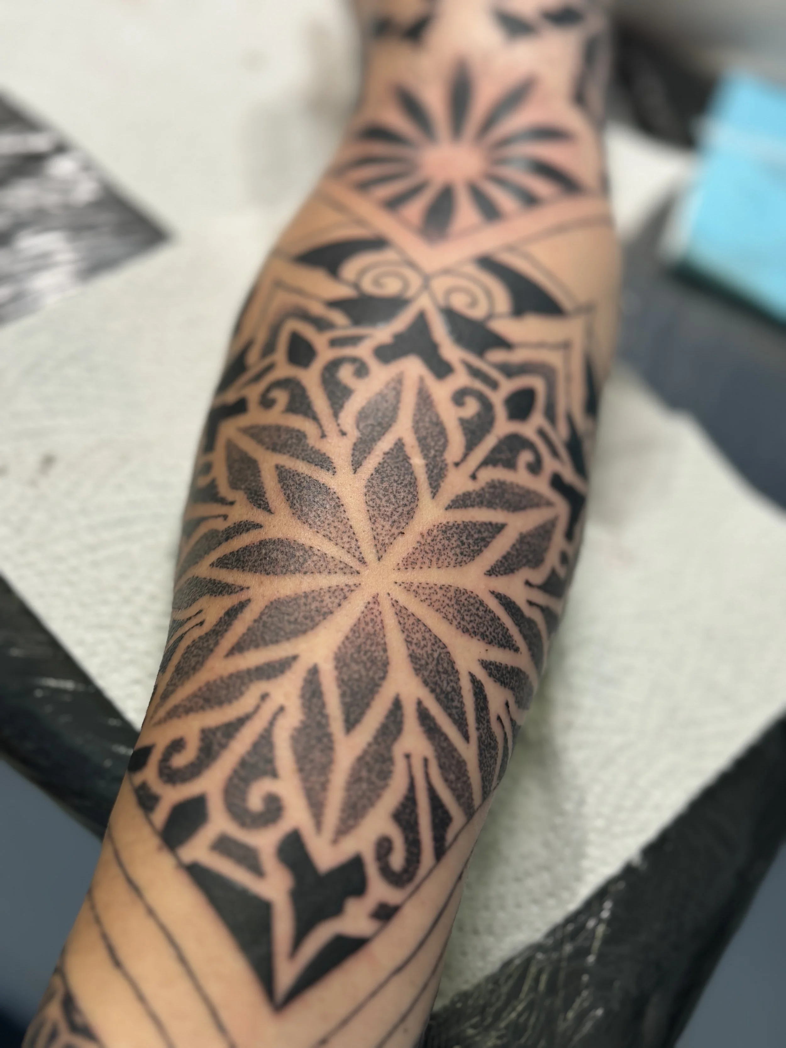 Dotwork-style tattoo covering a forearm, featuring a symmetrical pattern with sharp points and swirling accents.