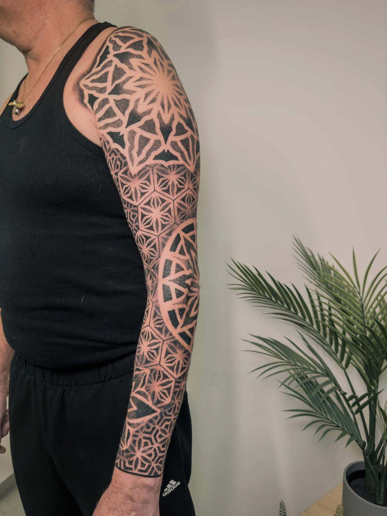Geometric blackwork full sleeve tattoo featuring detailed mandala patterns, dotwork shading and bold negative space, created by Carlo, a traveling tattoo artist specializing in fineline, floral and dotwork designs with a base in Belgium.