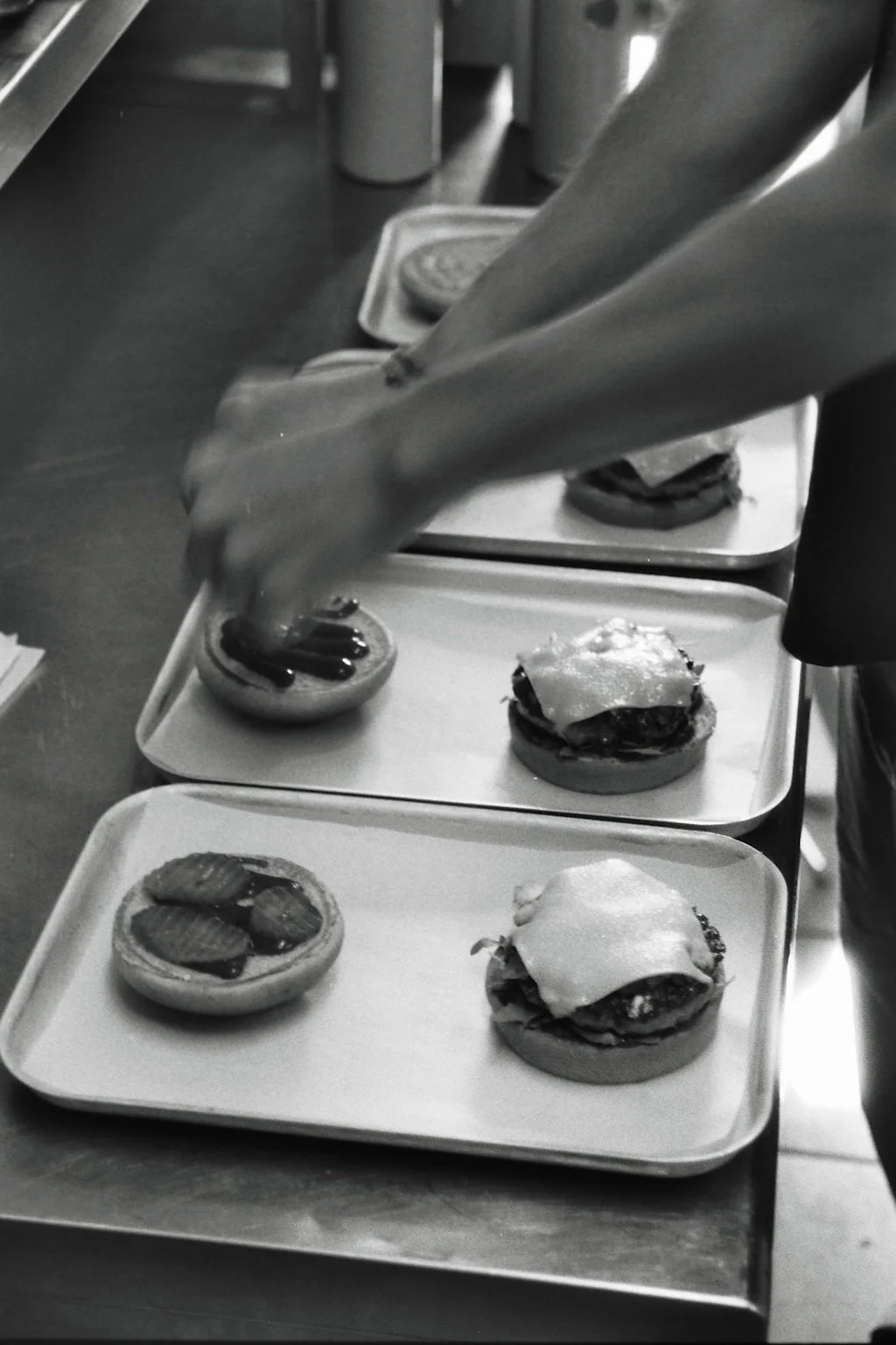 Mensch, der belegte Burger patties auf Tablett legt