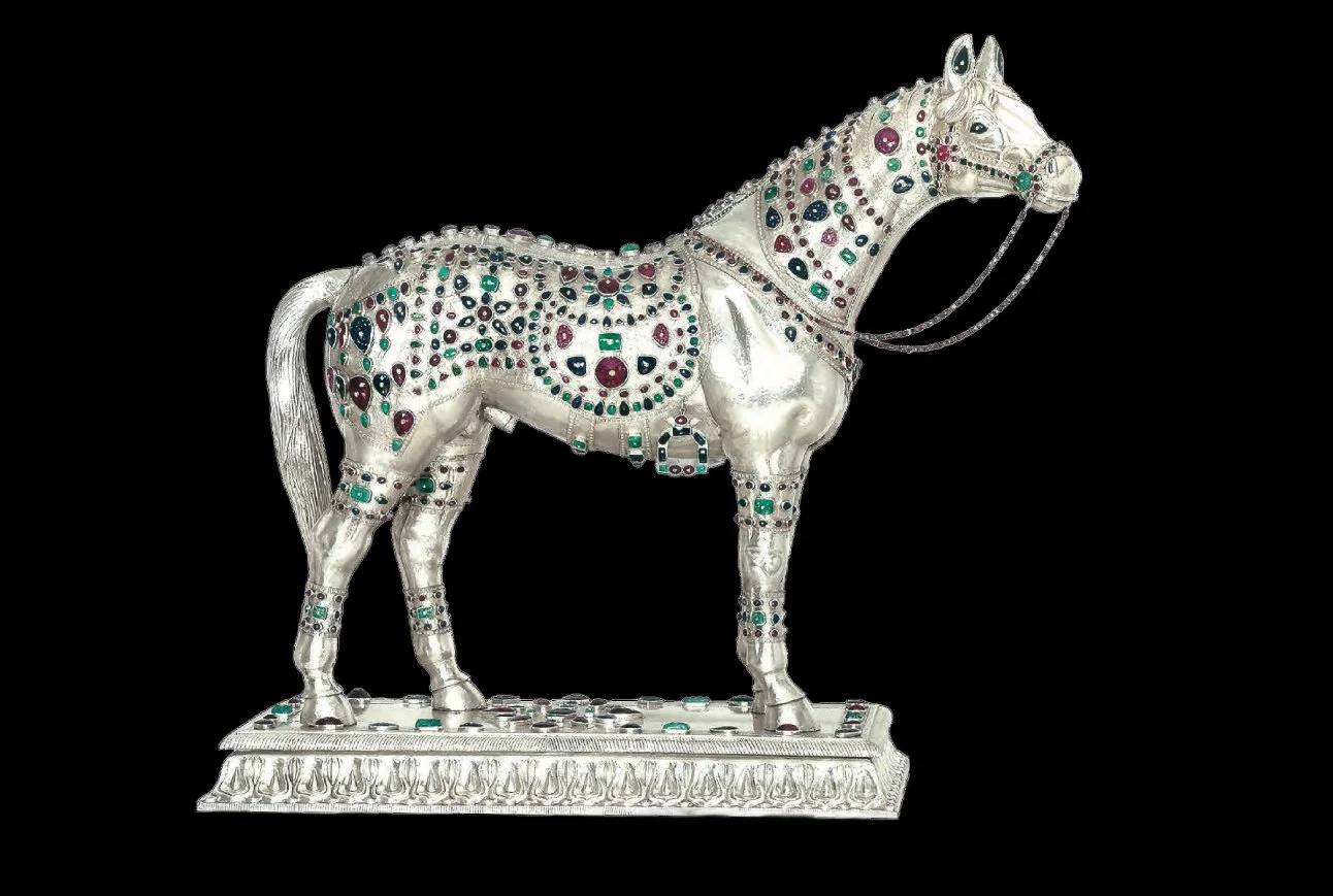 A decorative, jewel-encrusted silver horse sculpture with colorful gemstones on a black background.
