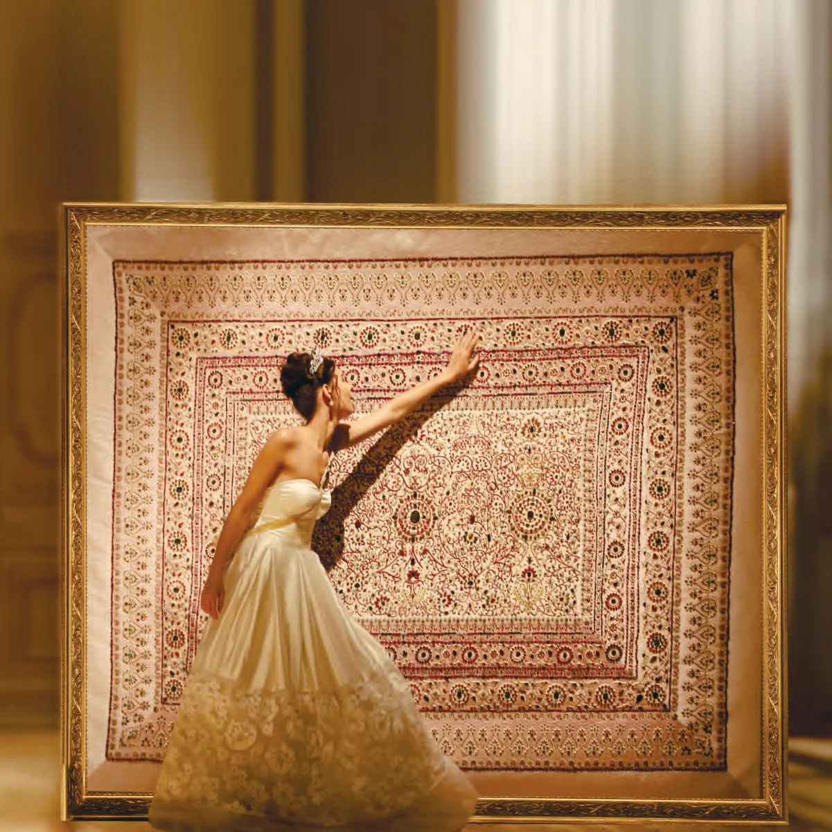 A woman in a white wedding dress standing in front of an ornate framed rug, reaching out to touch the rug.